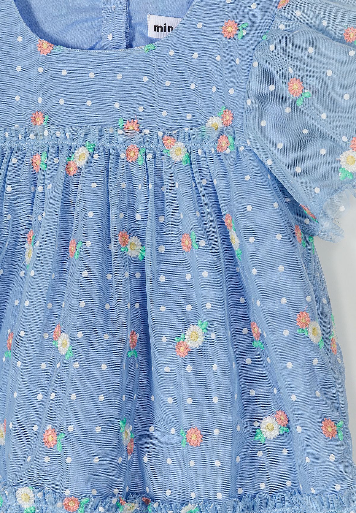 Detail of a girls' blue embroidered tulle dress with short sleeves and tiered skirt.