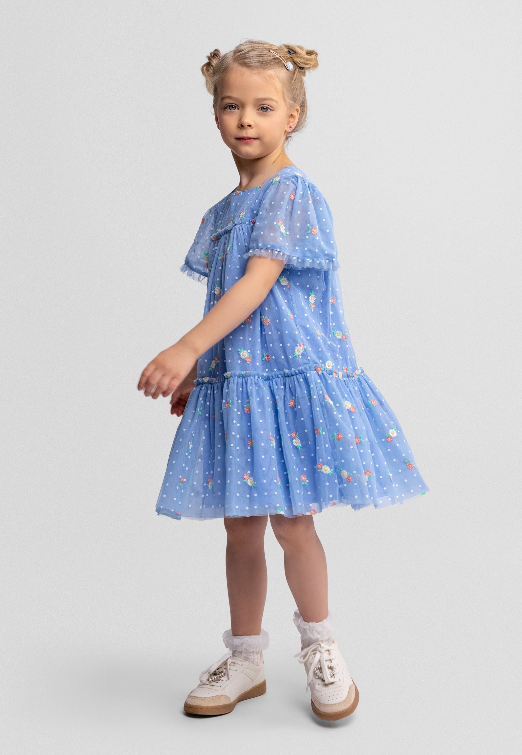 Back view of blue tulle dress showing button fastening, tiered layers and floral dot pattern on white background