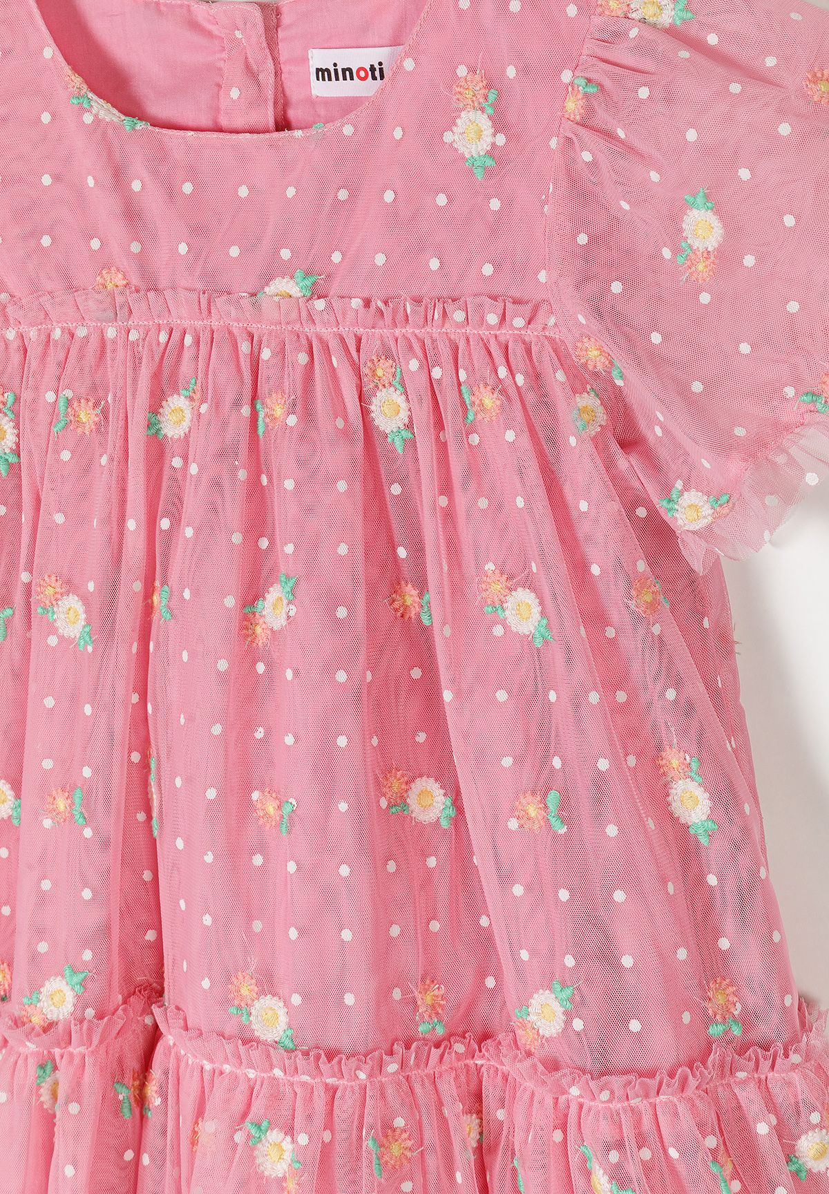 Detail of a girls' pink floral embroidered tulle dress with short sleeves and polka dots.