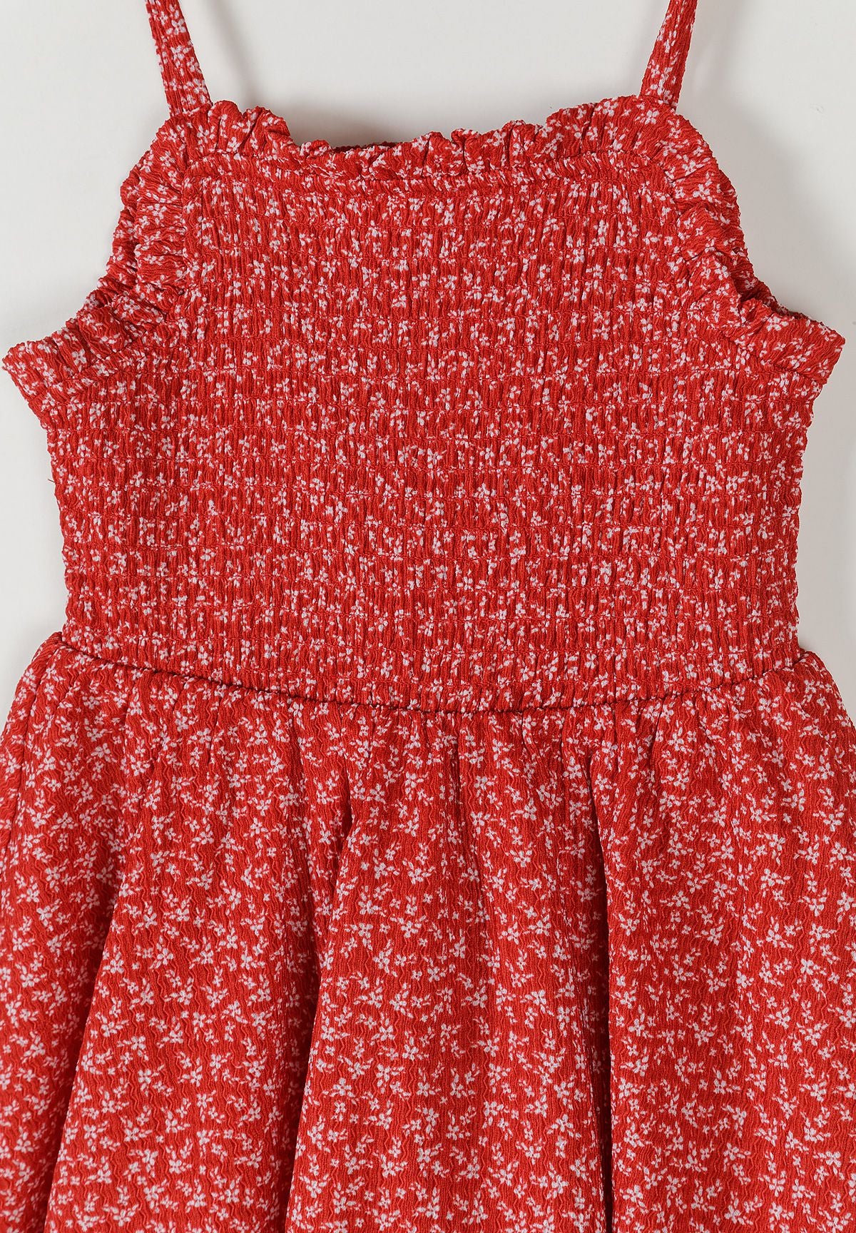Detail of a girls' red floral sleeveless summer dress with thin straps.