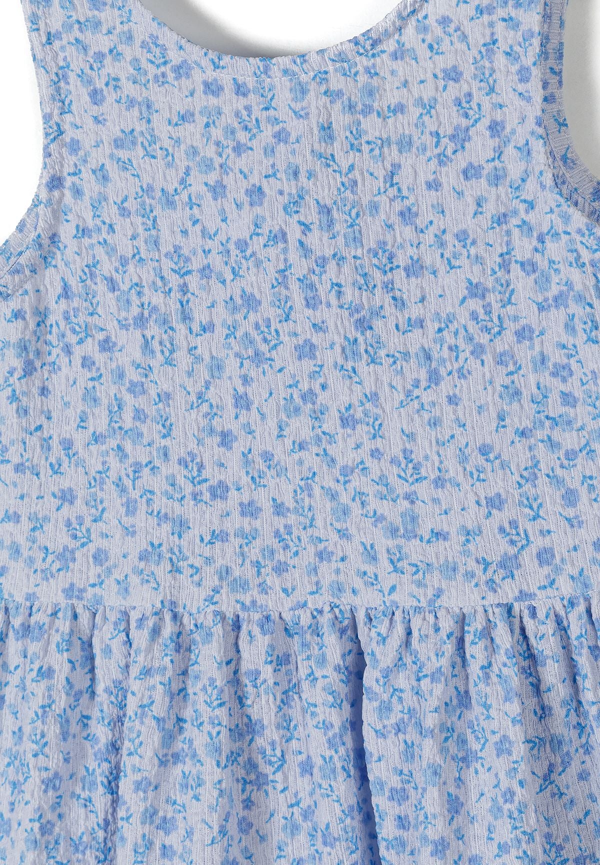 Detail of a girls' sleeveless blue floral summer dress with tiered design.