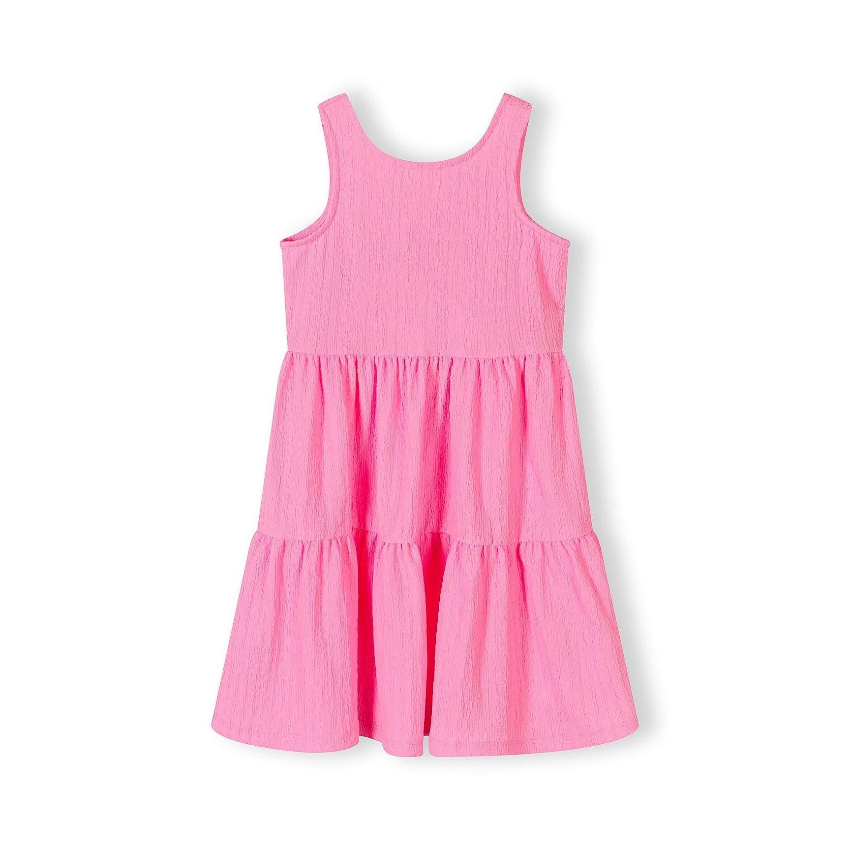 Bright pink tiered dress laid flat on white background showing sleeveless design and three-tier ruffle construction