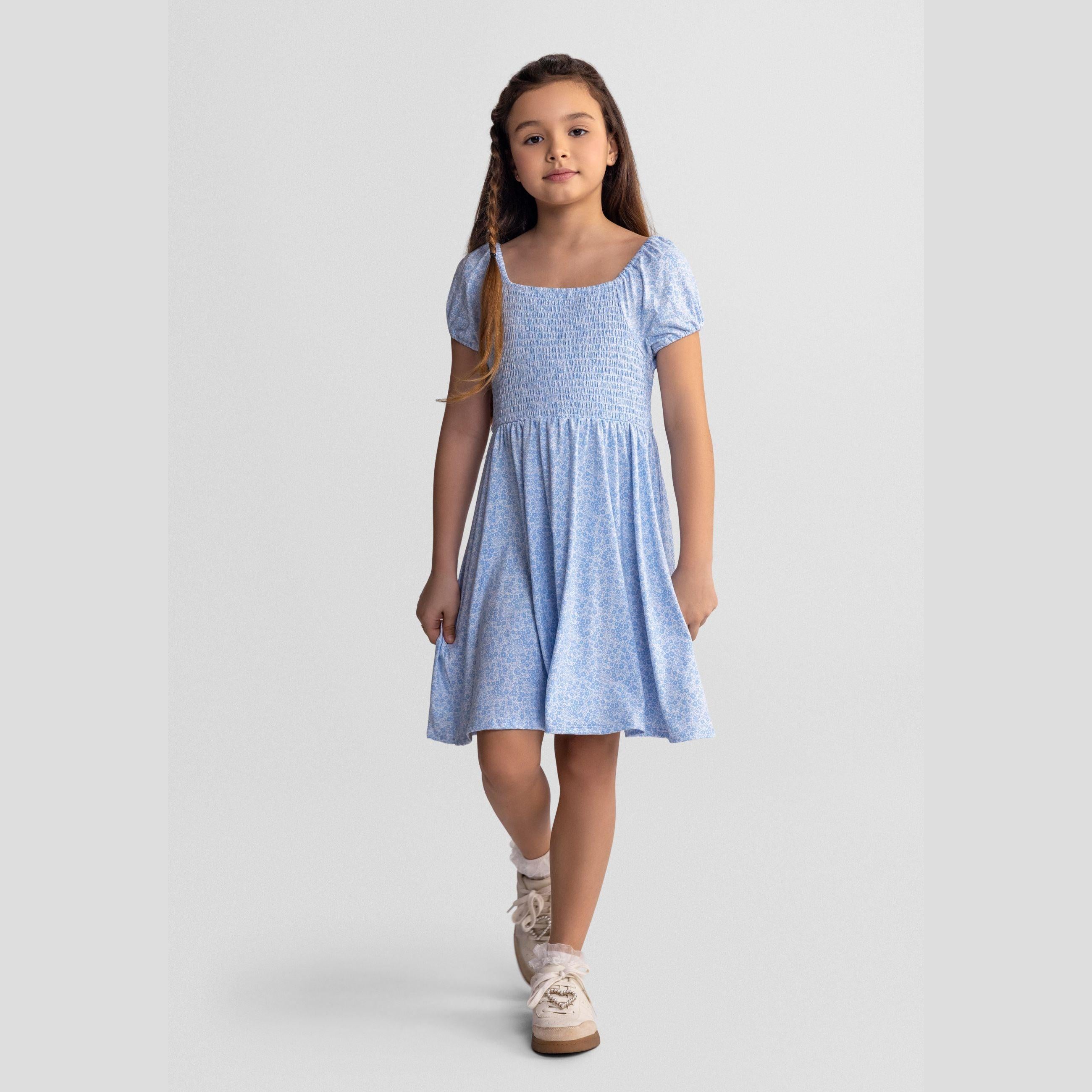 Light blue floral dress laid flat showing smocked bodice detail, short sleeves and flowing skirt on white background