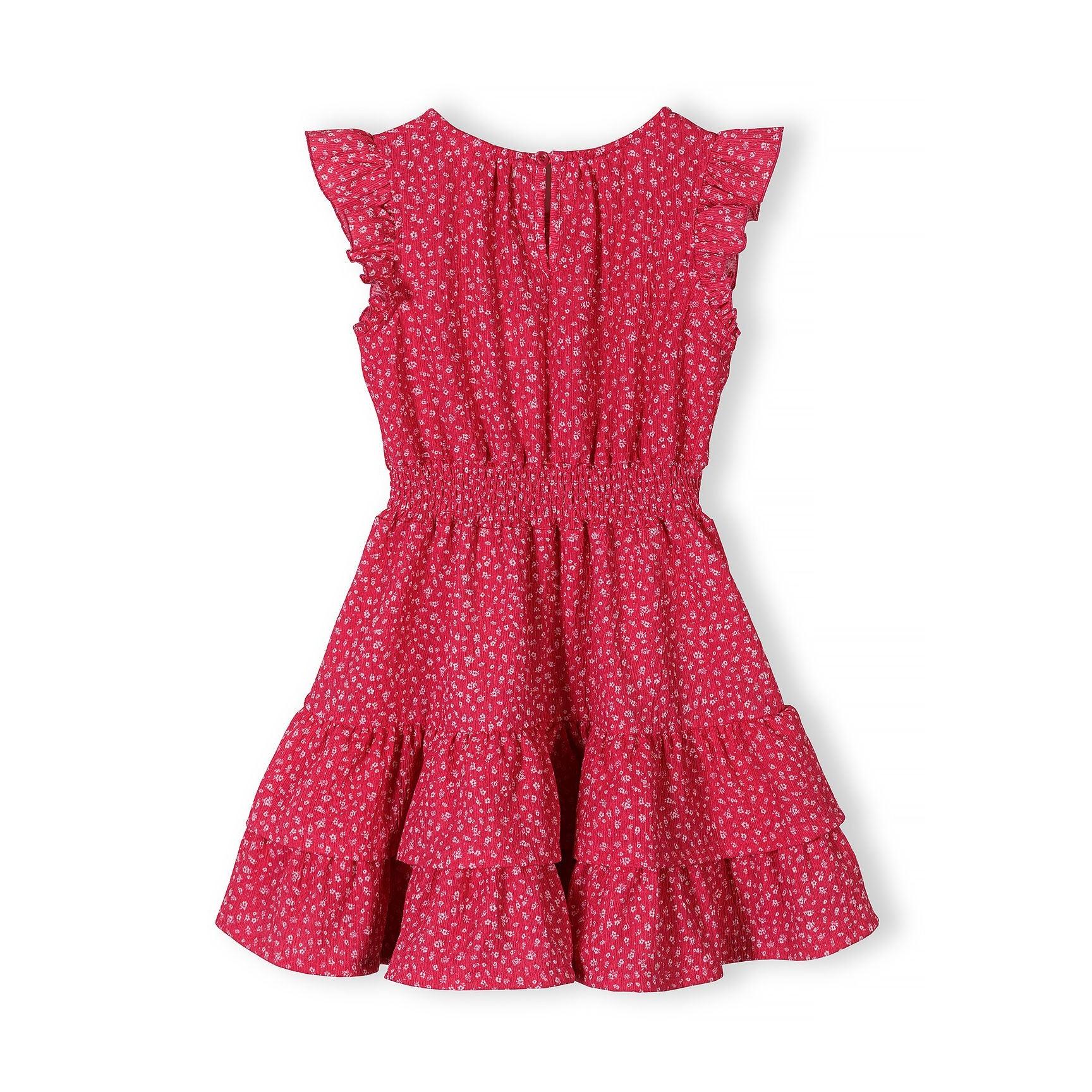 Close-up detail of pink dress showing Minoti label, elasticated waist construction, white floral print pattern and fabric texture