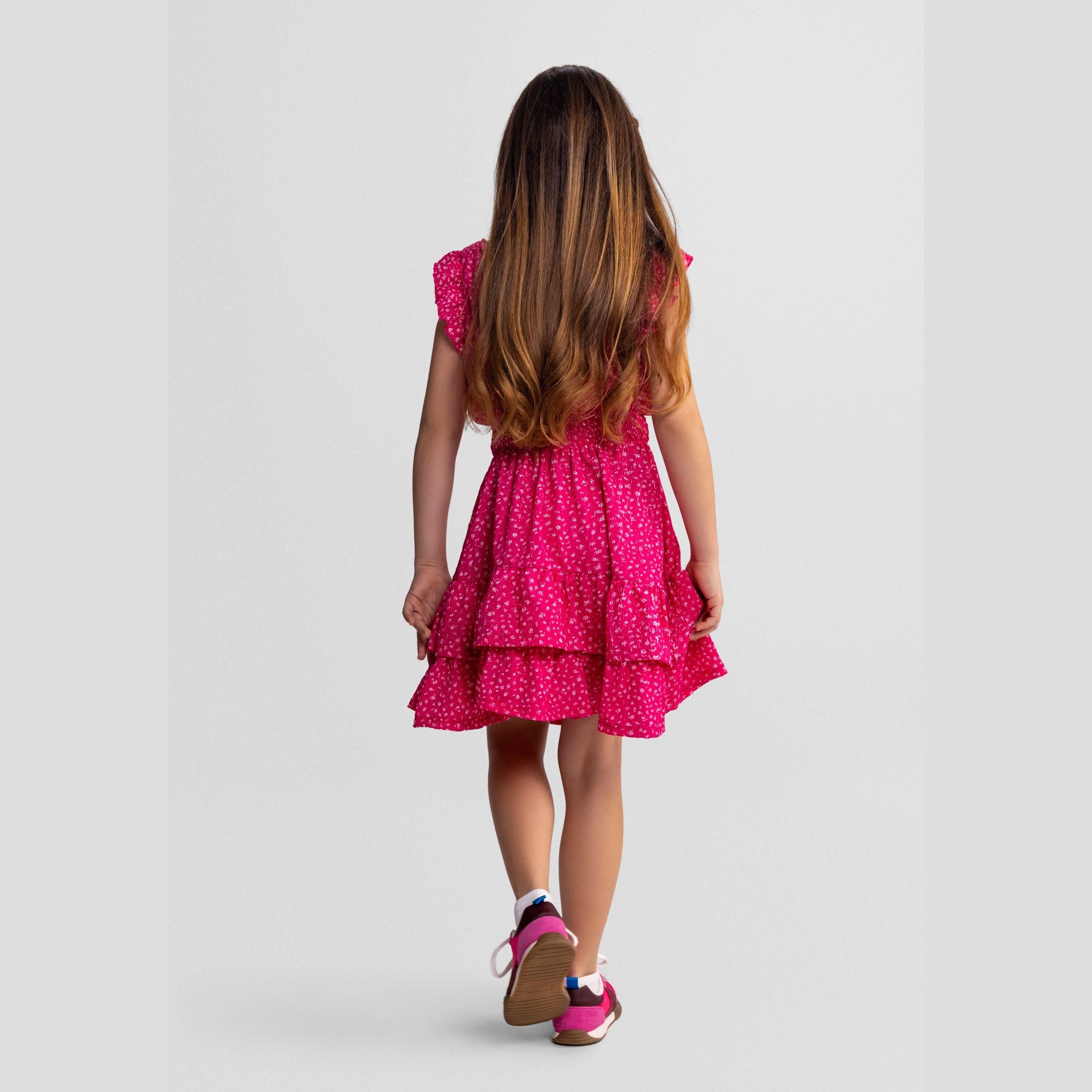 Close-up detail of pink dress showing Minoti label, elasticated waist construction, white floral print pattern and fabric texture