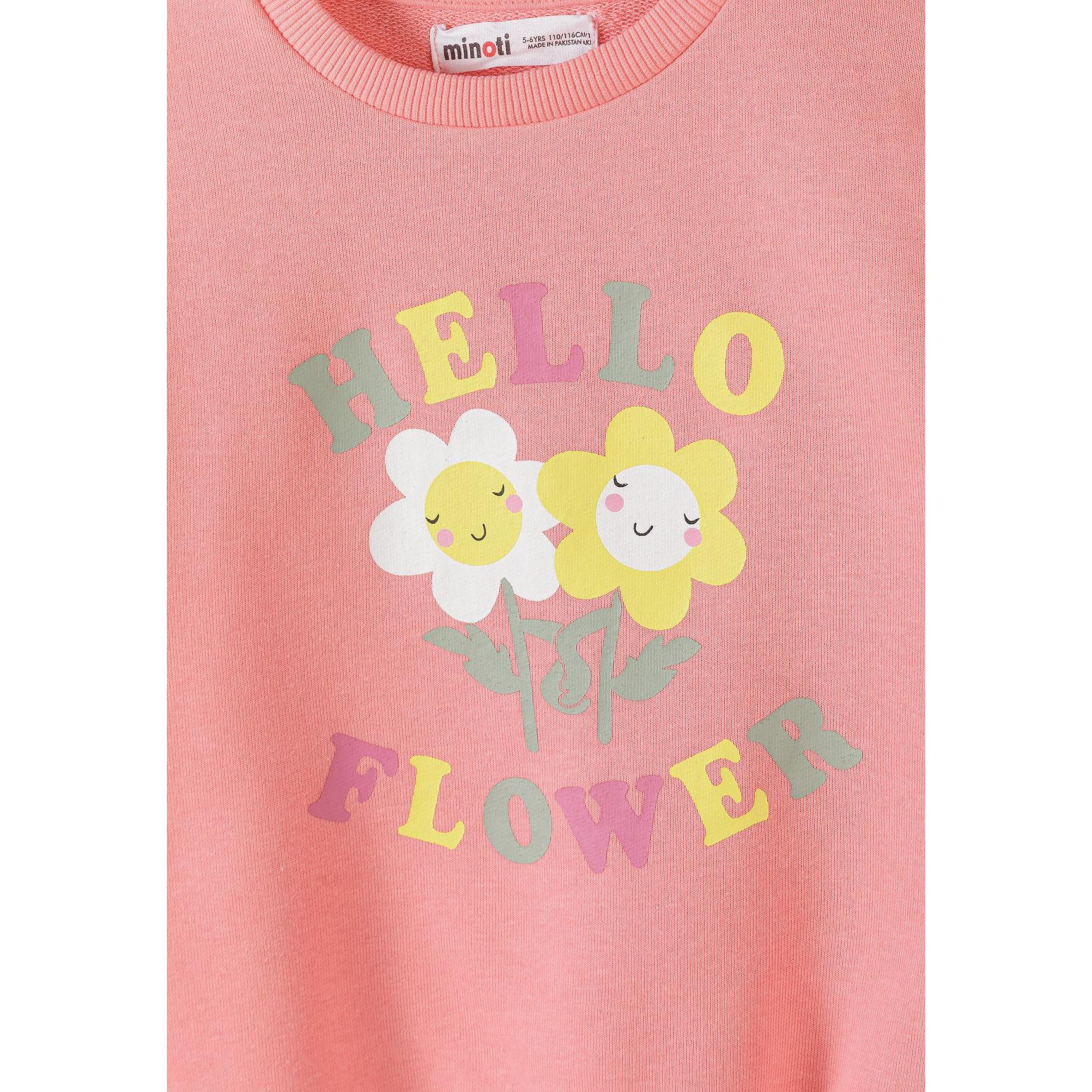 Close-up detail of coral pink sweatshirt showing Hello Flower text with smiling daisy graphics and Minoti label at neckline