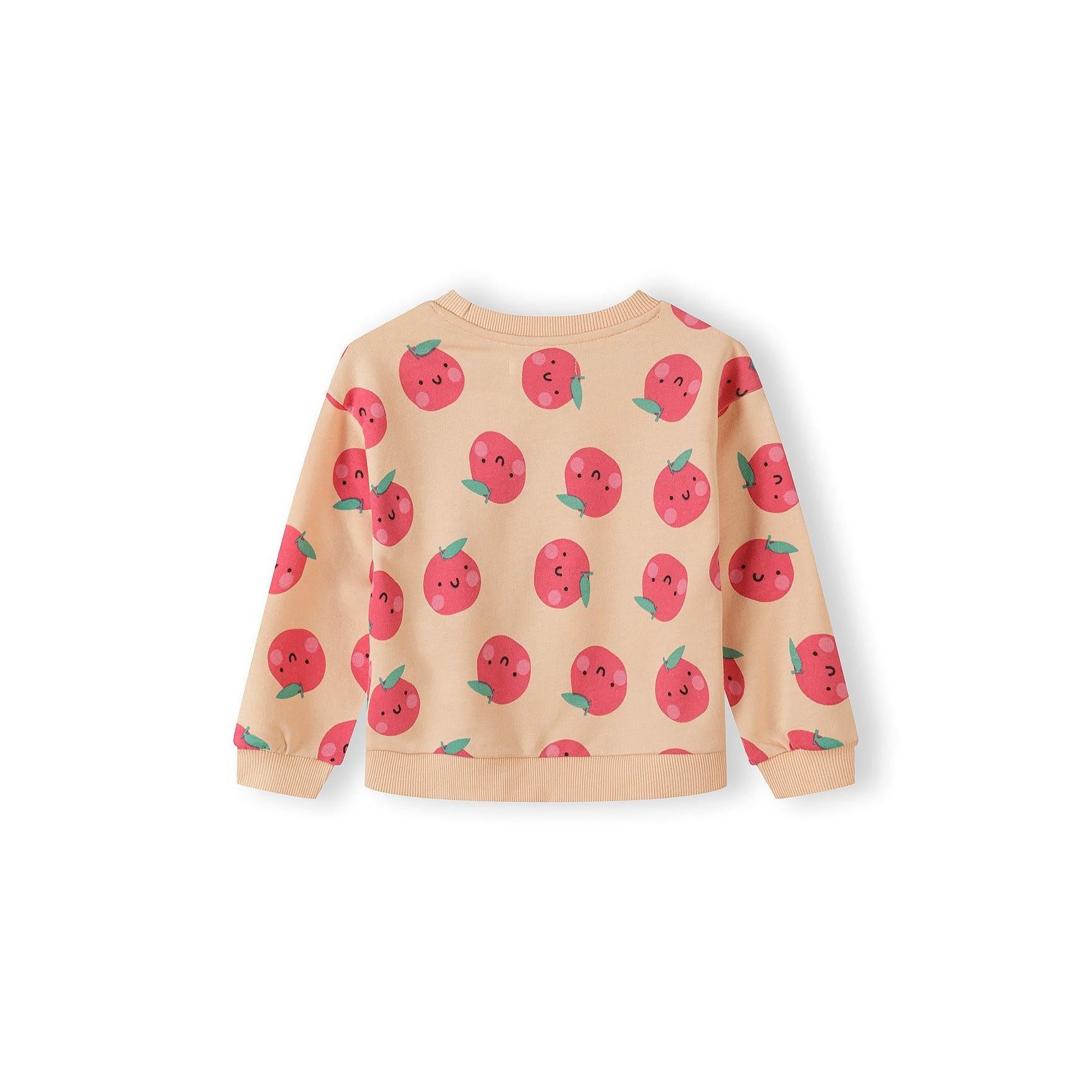 Detail shot of apricot sweatshirt showing cute kawaii-style apple print with smiling faces, green leaves and ribbed neckline