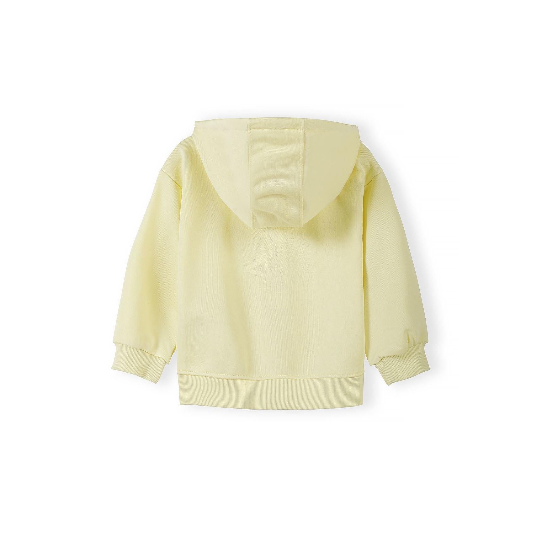 Detail shot showing Minoti label and embroidered heart design on pale yellow hoodie fabric with zip fastening visible