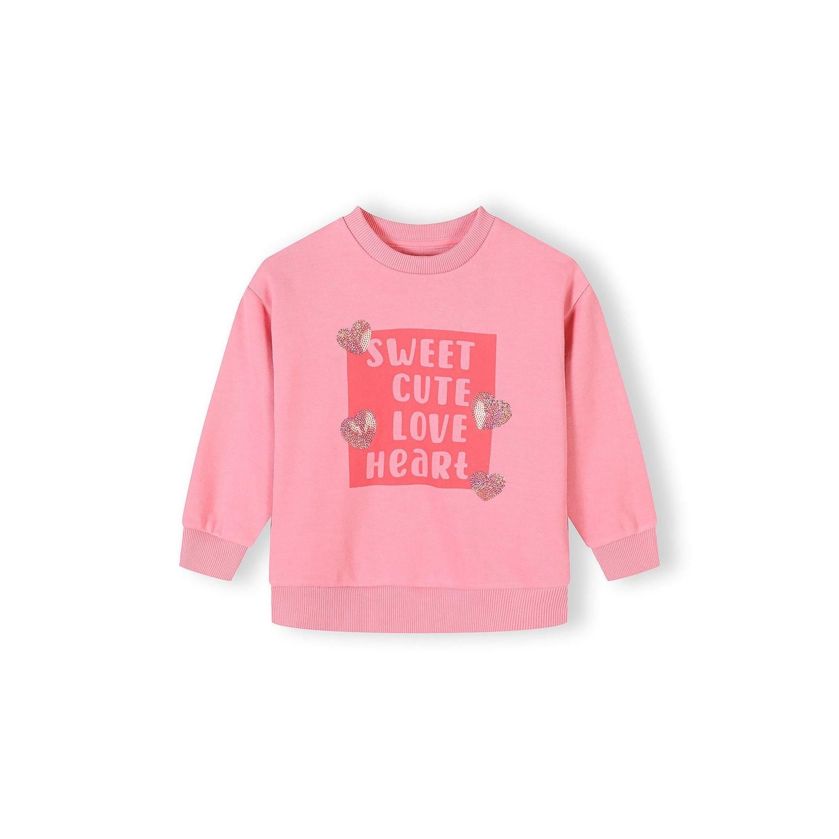Close-up detail of pink sweatshirt front showing 'Sweet Cute Love Heart' text print in coral rectangle with sequined heart embellishments scattered around