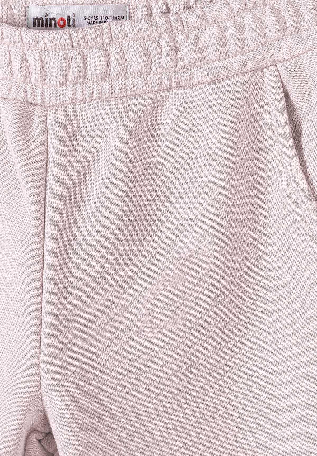 Close-up of pale pink joggers' gathered waistband, front seam and side pocket opening.
