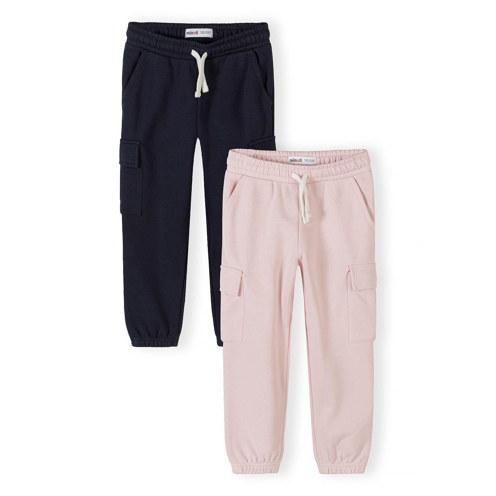 Two pairs of Minoti cargo joggers displayed flat - navy blue joggers with white drawstring on left, light pink joggers with white drawstring on right, both featuring side cargo pockets and elasticated cuffs on white background