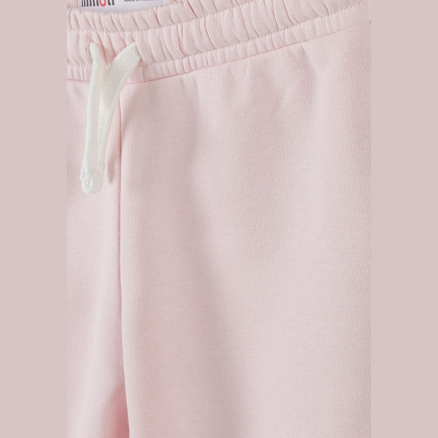 Close-up detail of light pink joggers showing elastic waistband with white drawstring and Minoti label on pink fabric background