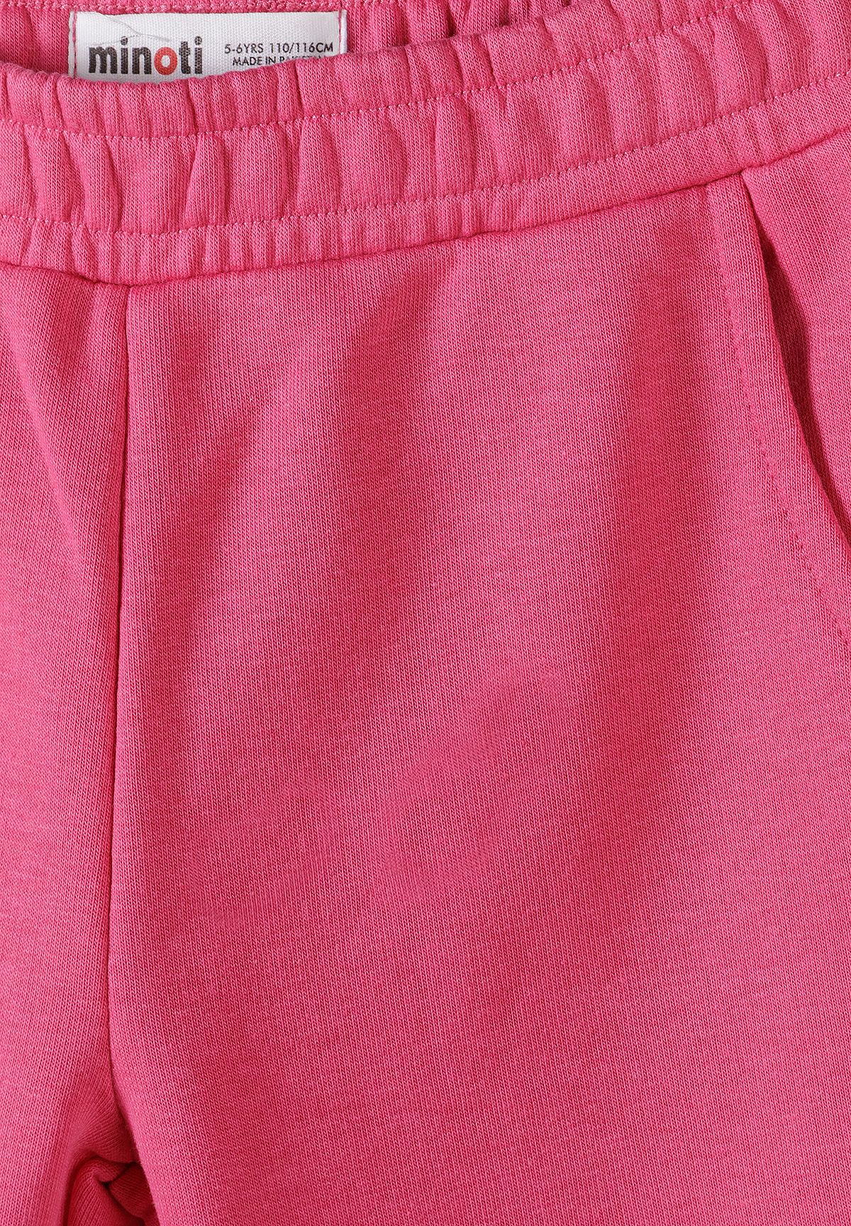 Close-up of bright pink girls' joggers showing the gathered elastic waistband, Minoti label and curved side pocket opening.