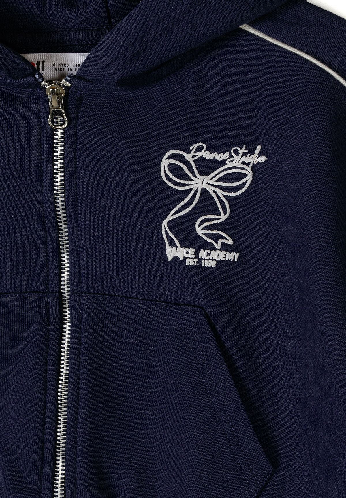 Close-up of navy blue zip-up jacket with hood and logo detail.