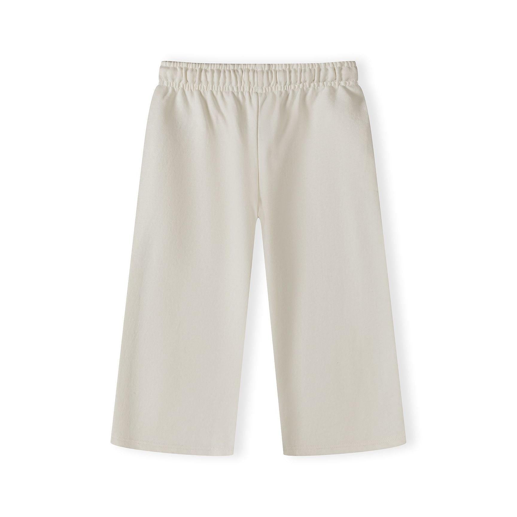 Close-up detail of beige wide-leg tracksuit trousers showing elastic waistband with drawstring and navy embroidered logo