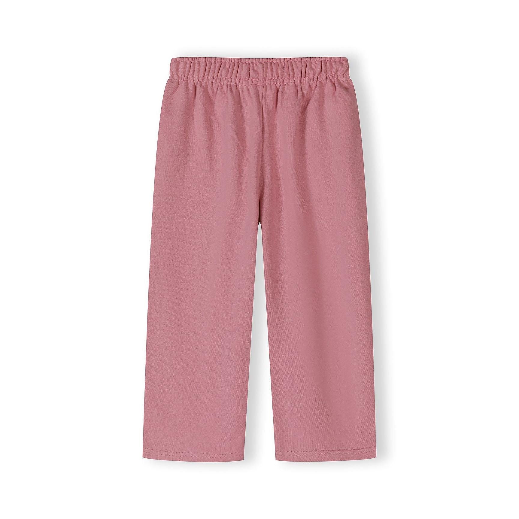 Detail shot showing Minoti brand label and elastic waistband construction of pink wide-leg joggers with text print