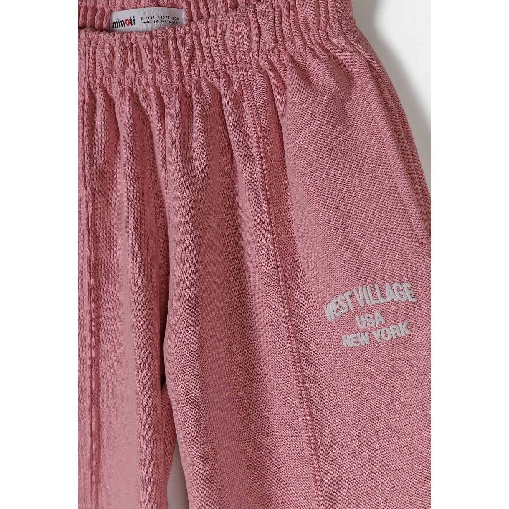 Detail shot showing Minoti brand label and elastic waistband construction of pink wide-leg joggers with text print