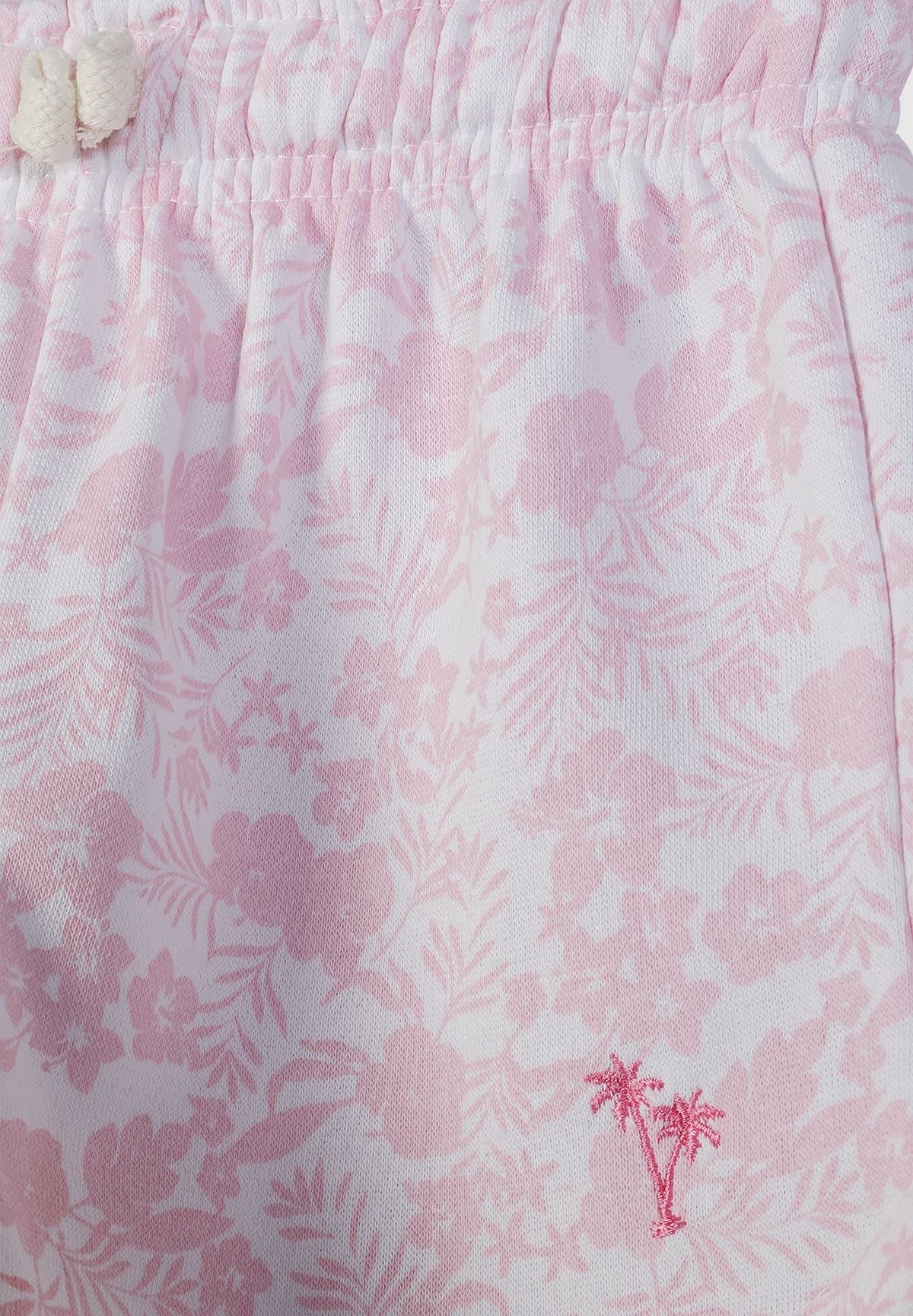 Detail of white shorts with pink tropical embroidery and elastic waistband.