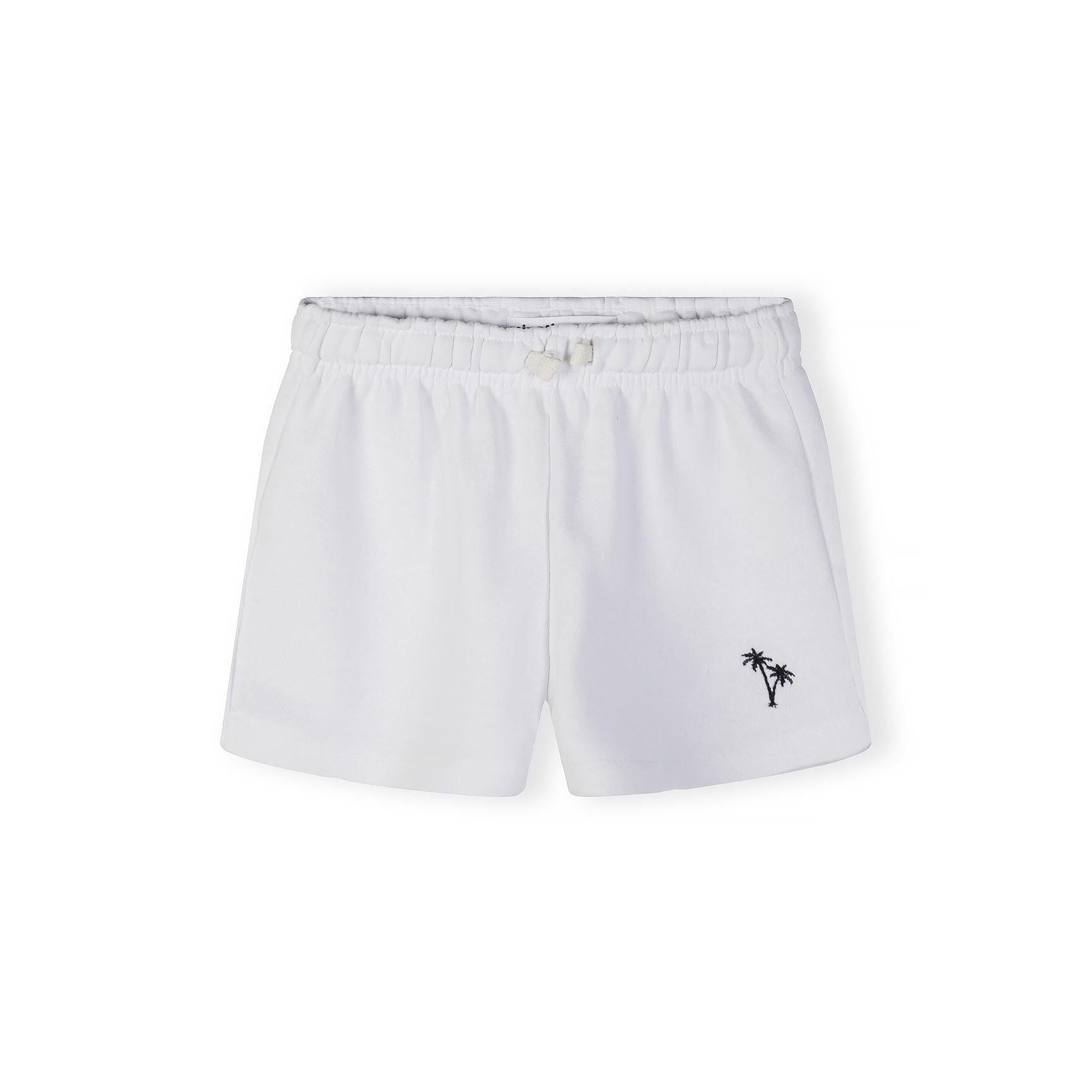 Close-up detail of tropical floral print pattern in pink and white with small pink palm tree embroidery visible on fabric