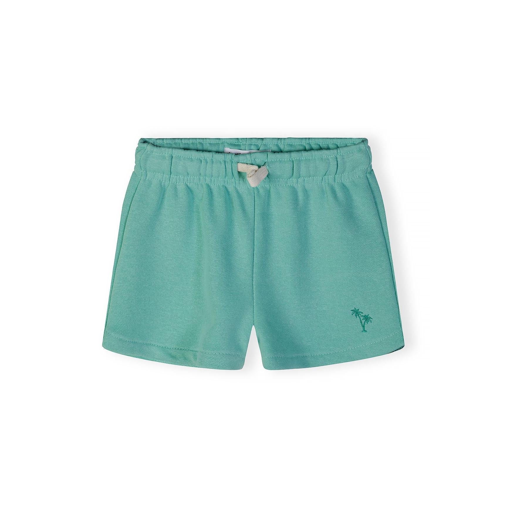 Close-up of mint green shorts showing embroidered palm tree detail and white bow tie at elasticated waistband