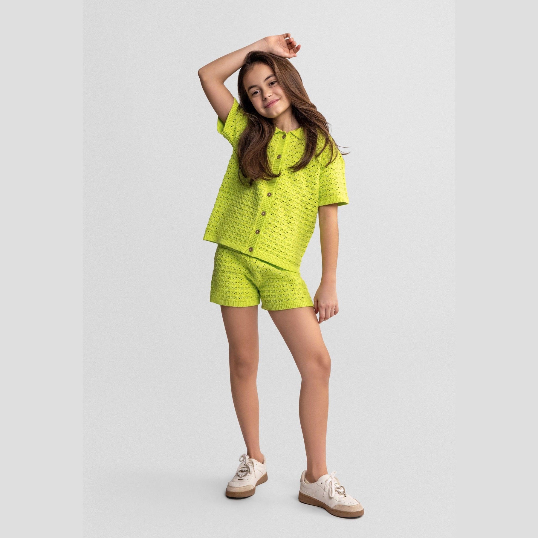 Back view of lime green pointelle knit short-sleeve top showing detailed textured stitch pattern and classic silhouette on white background