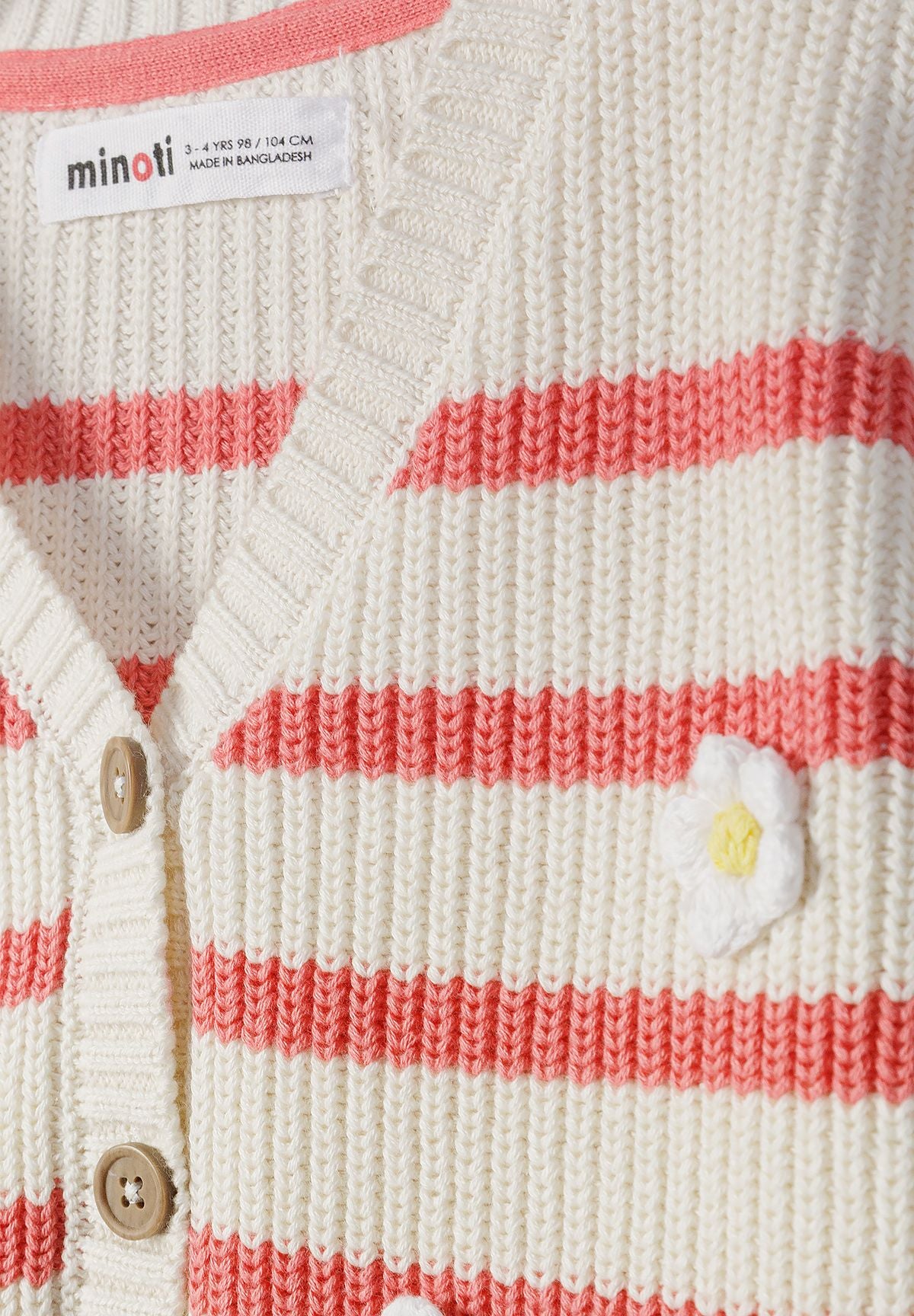 Close-up of coral striped cardigan's white daisy and tan buttons.