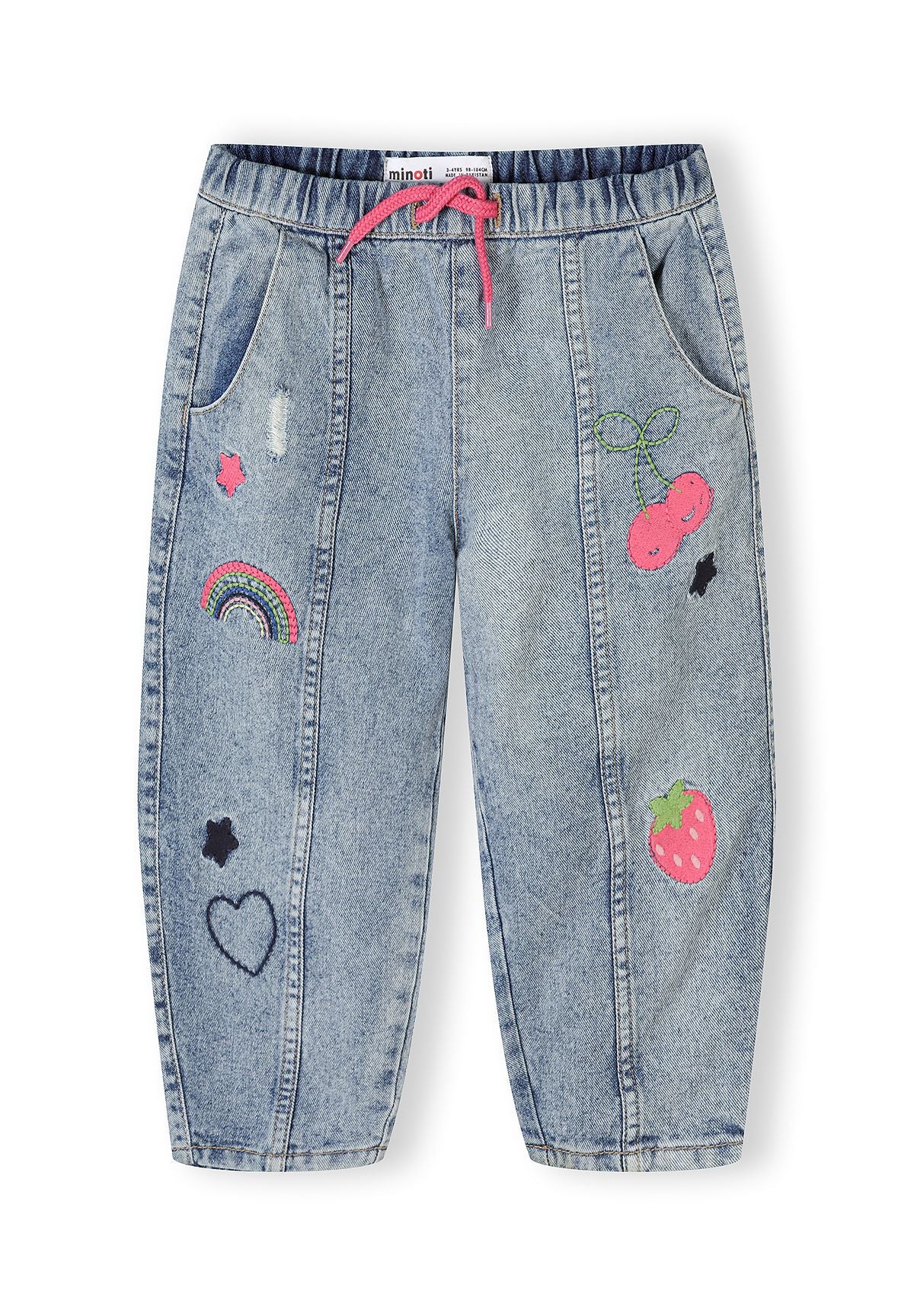 Close-up flat lay of blue denim barrel leg jeans showing elastic waistband with pink drawstring and embroidered details including rainbows and fruits