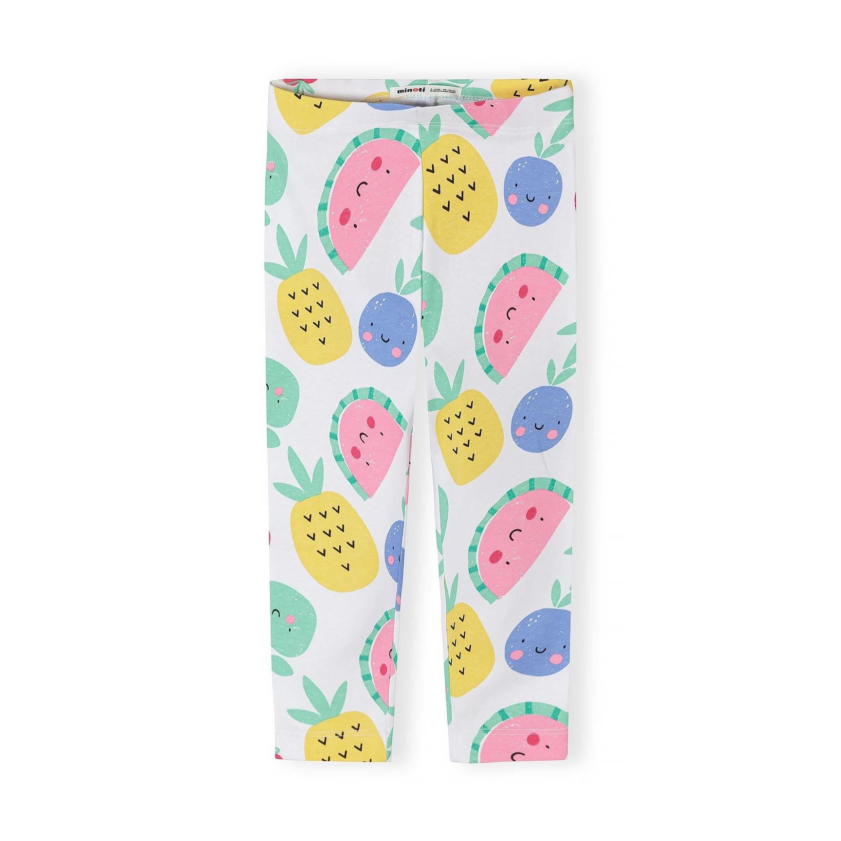 Close-up detail of white leggings with colorful fruit print showing smiling pineapples, watermelons and blueberries with Minoti label visible
