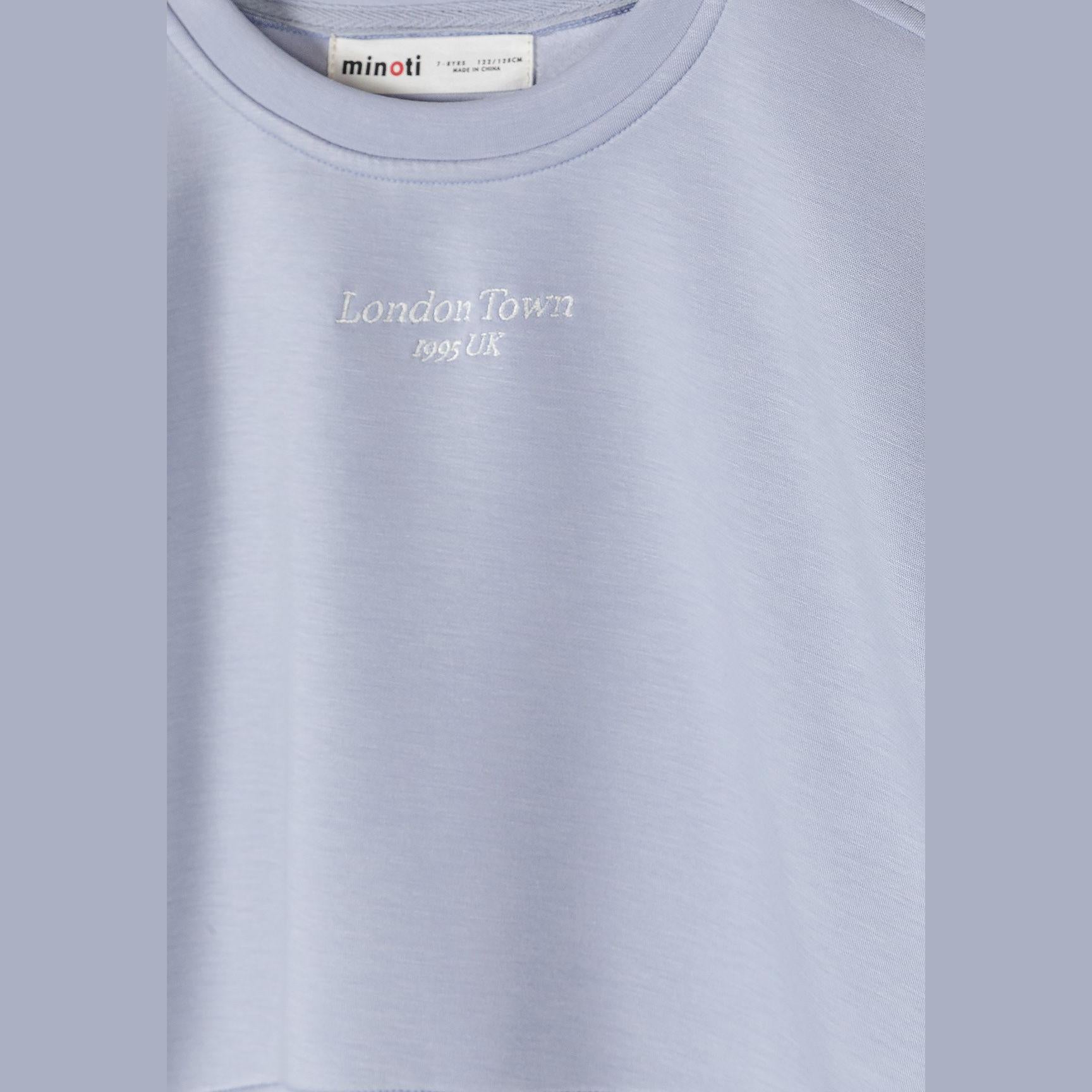 Close-up detail of light blue sweatshirt showing Minoti label and London Tower 1953 UK embroidery on chest
