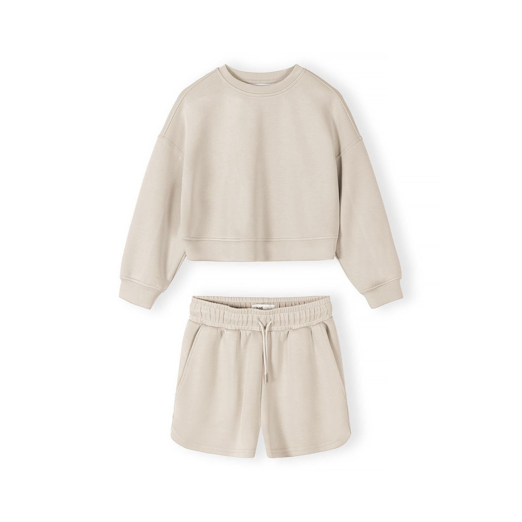 Close-up detail of beige shorts showing elasticated waistband with drawstring ties on neutral background