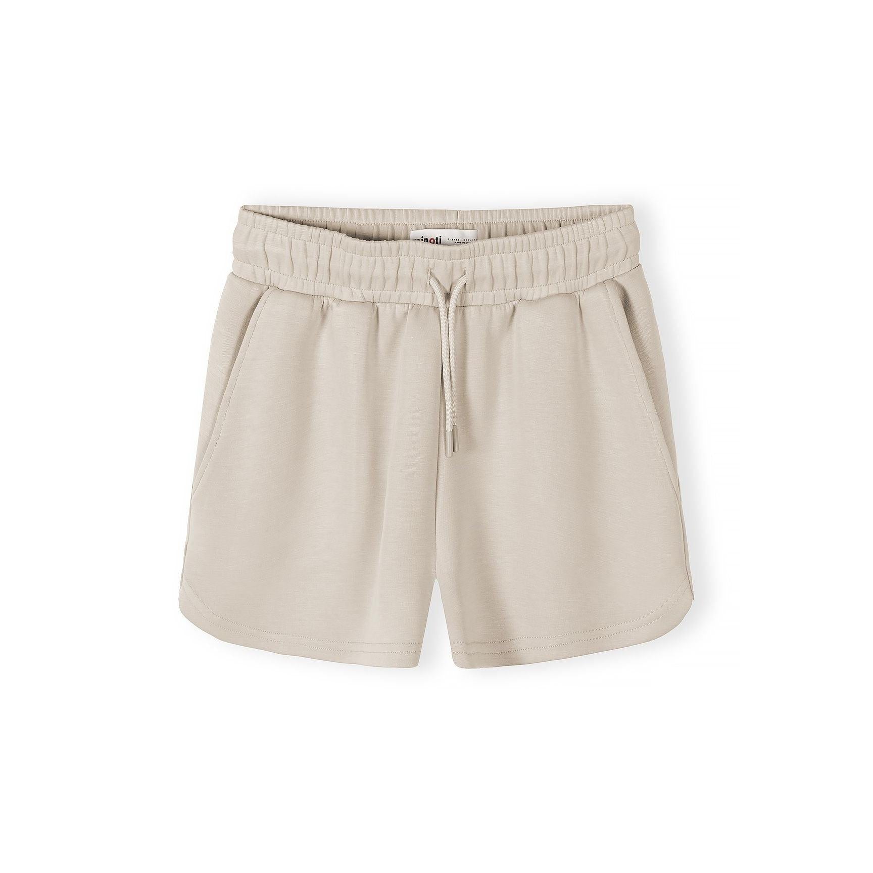 Close-up detail of beige shorts showing elasticated waistband with drawstring ties on neutral background