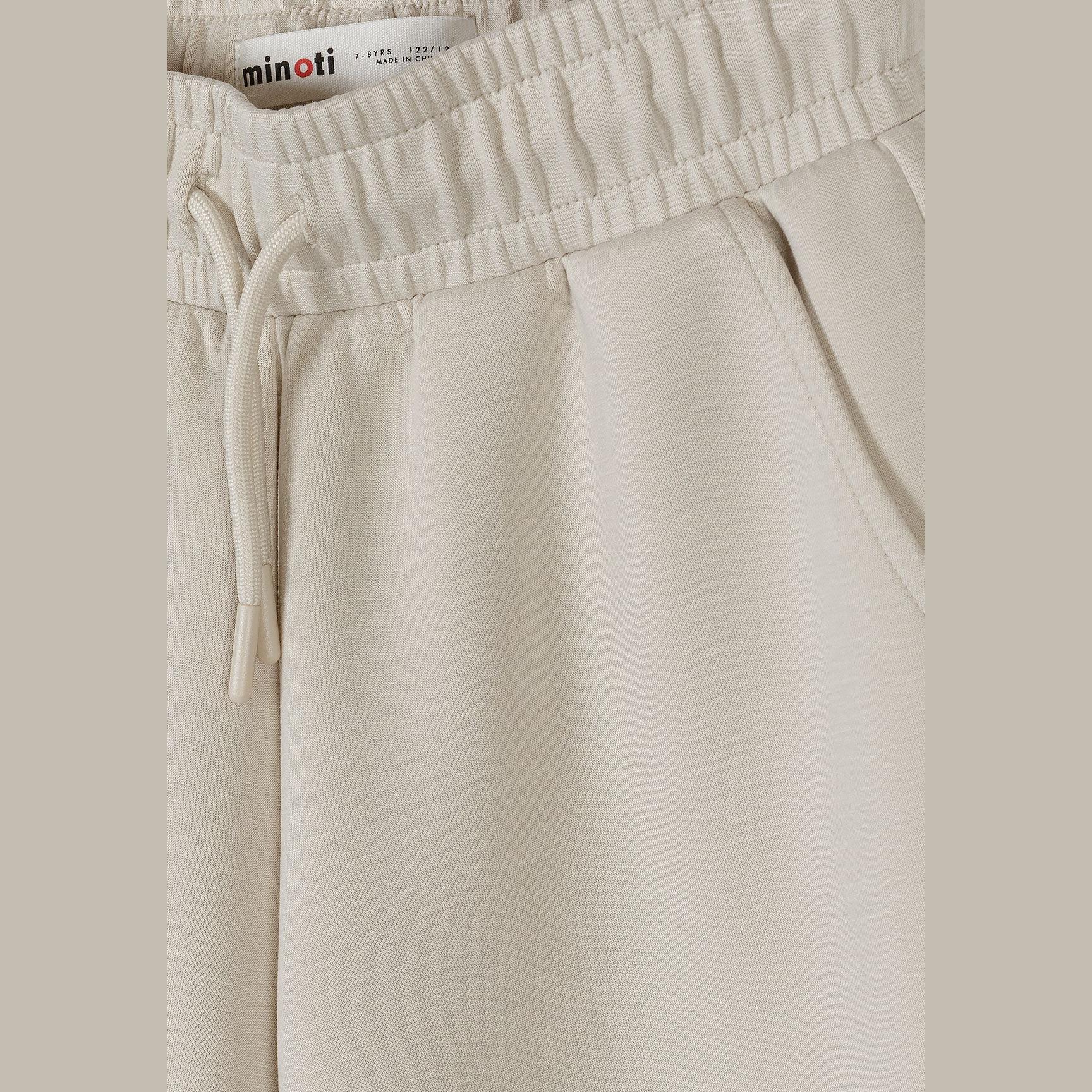 Close-up detail of beige joggers waistband showing Minoti label and adjustable drawstring ties with elastic waist