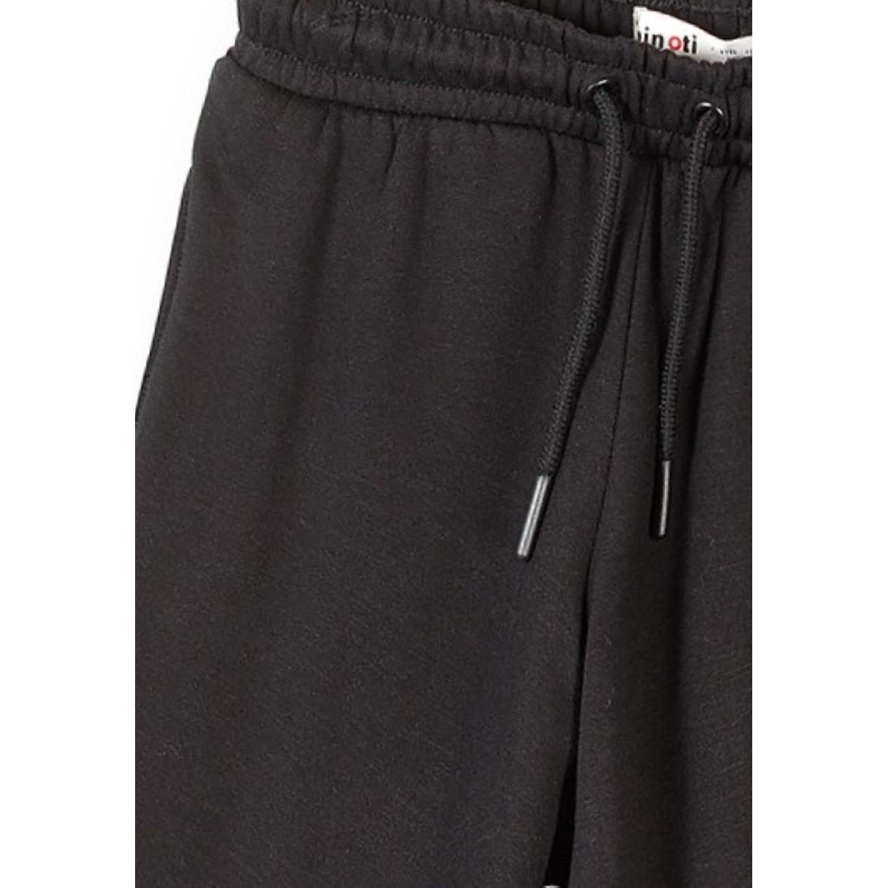 Close-up detail of black joggers showing elastic waistband with drawstring, side pocket and Minoti brand label