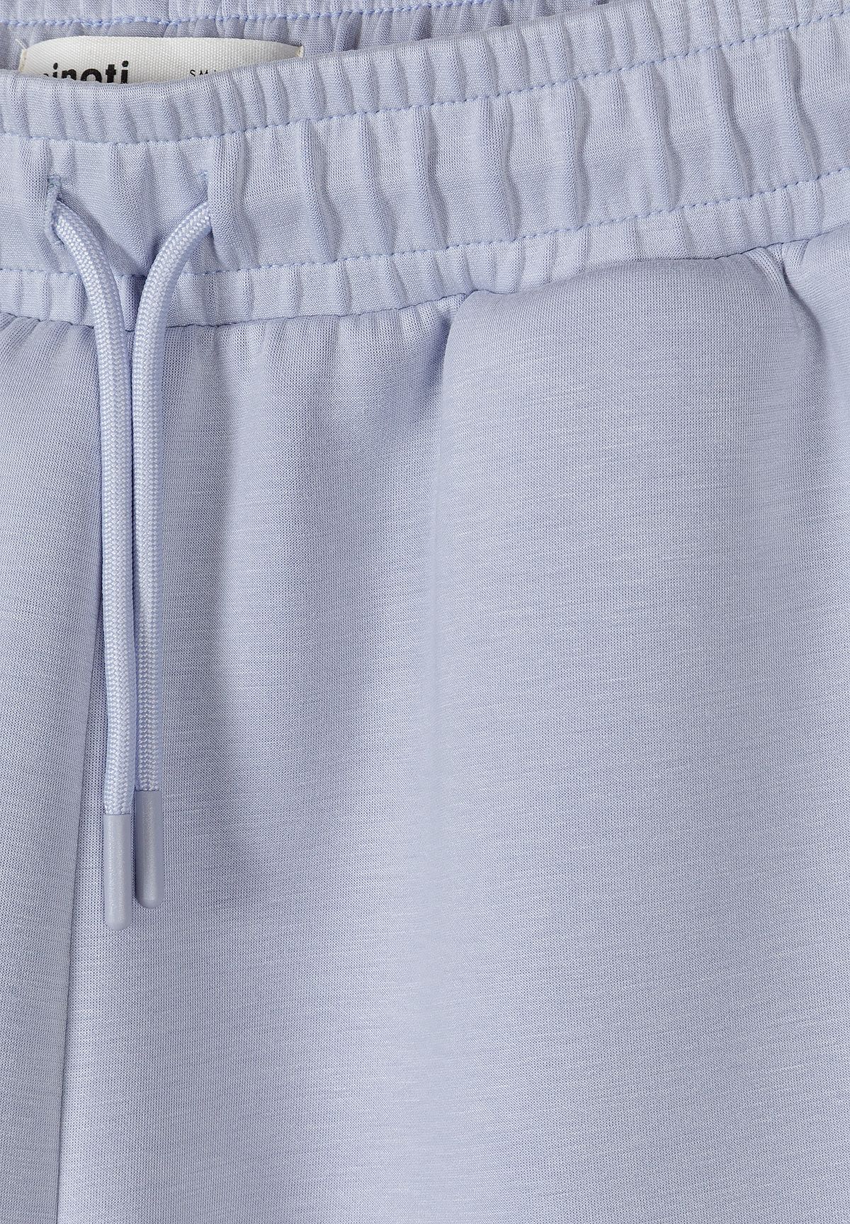 Close-up of matching shorts' gathered waistband, drawcord and smooth pale blue fabric.