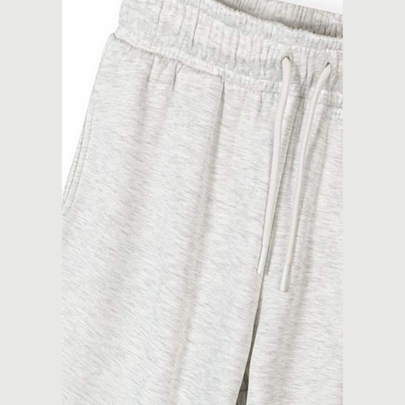 Close-up detail of light grey joggers showing elasticated waistband with drawstring ties and side pocket on white background