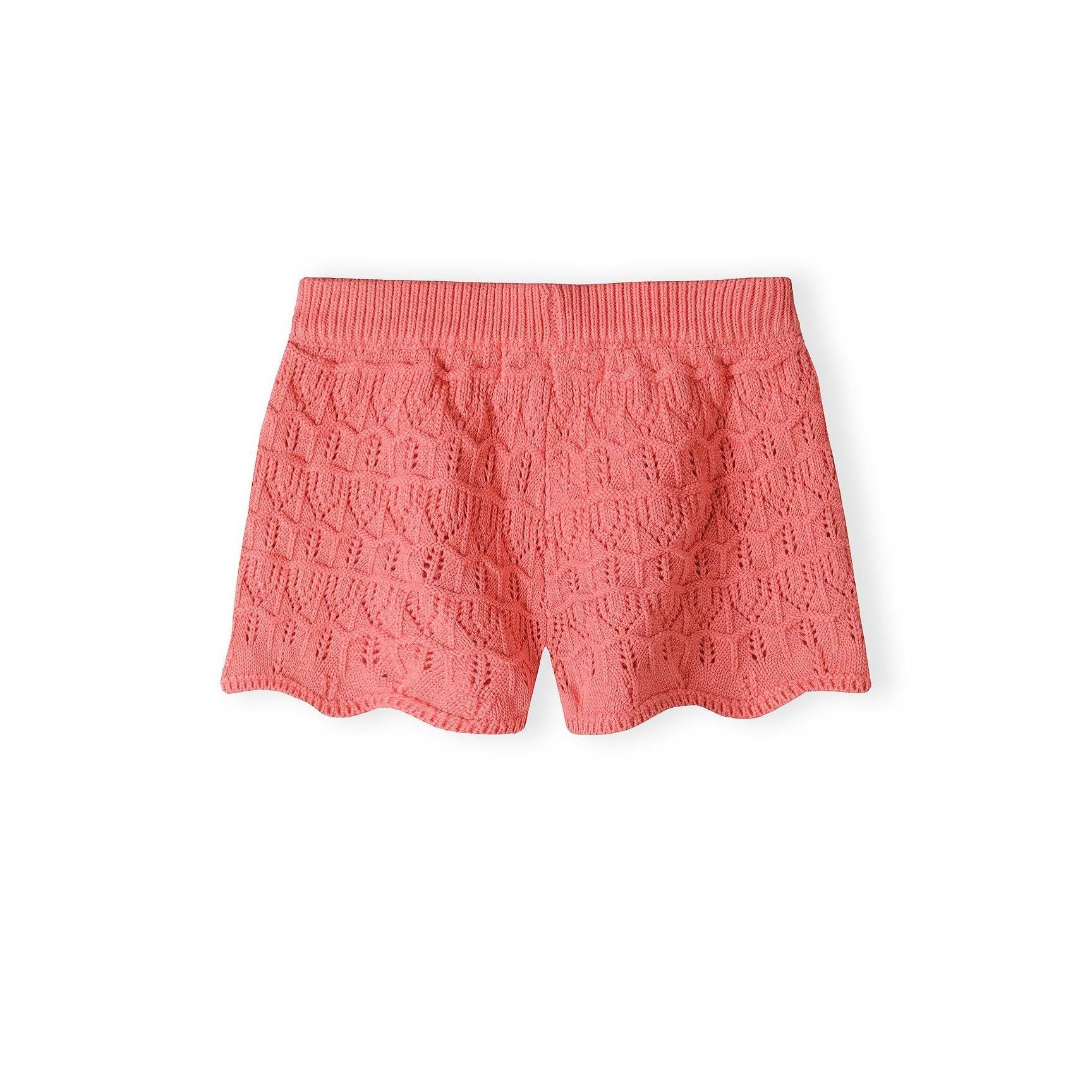 Detailed texture shot of coral pink crochet fabric showing intricate leaf and diamond pattern stitching