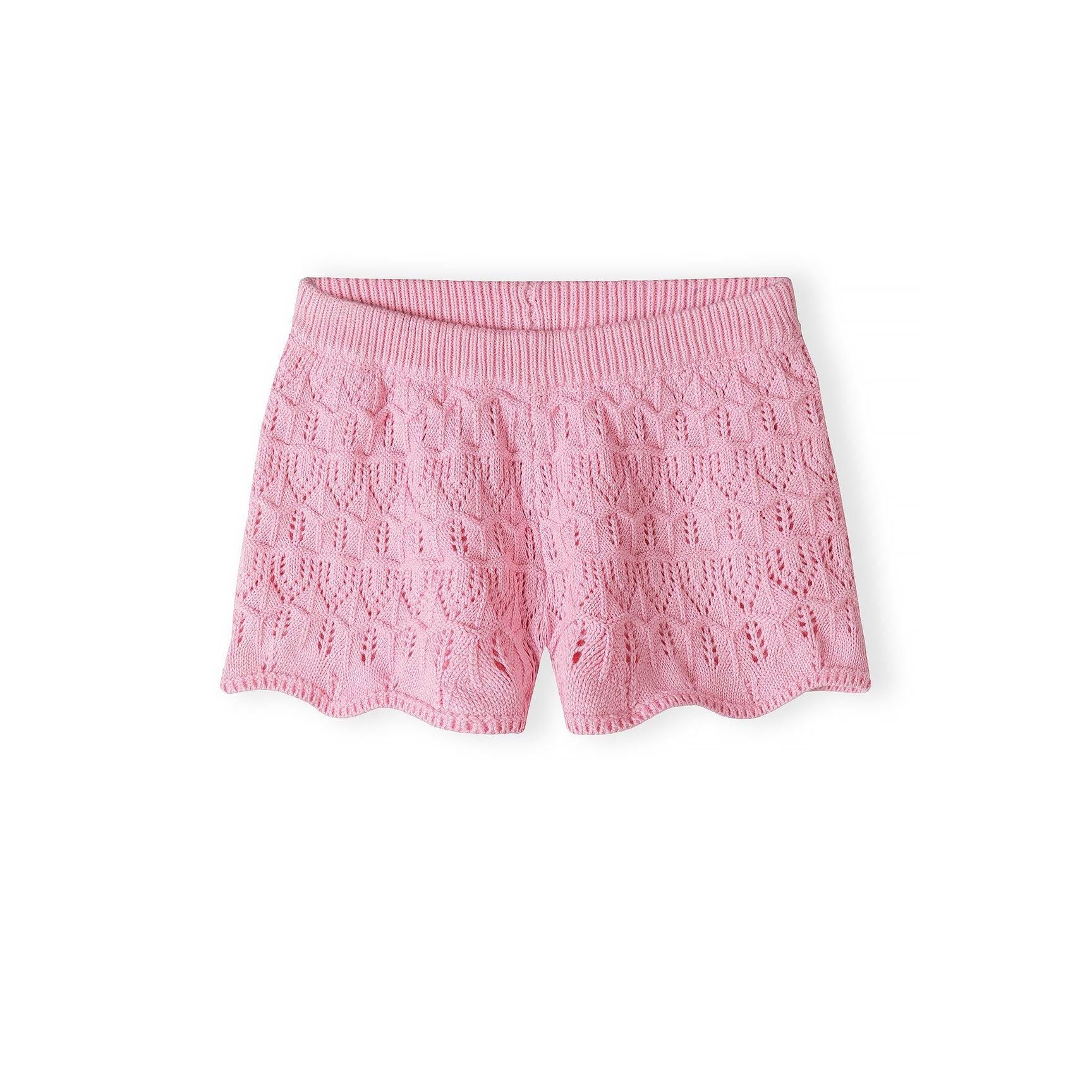 Close-up detail of pink crochet fabric showing intricate openwork stitch pattern with ribbed trim at top edge