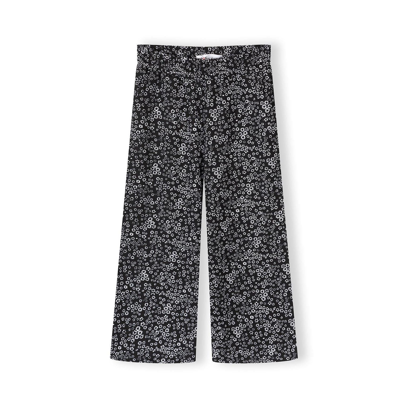 Close-up view of black wide-leg trousers with delicate white floral pattern, displayed flat on white background