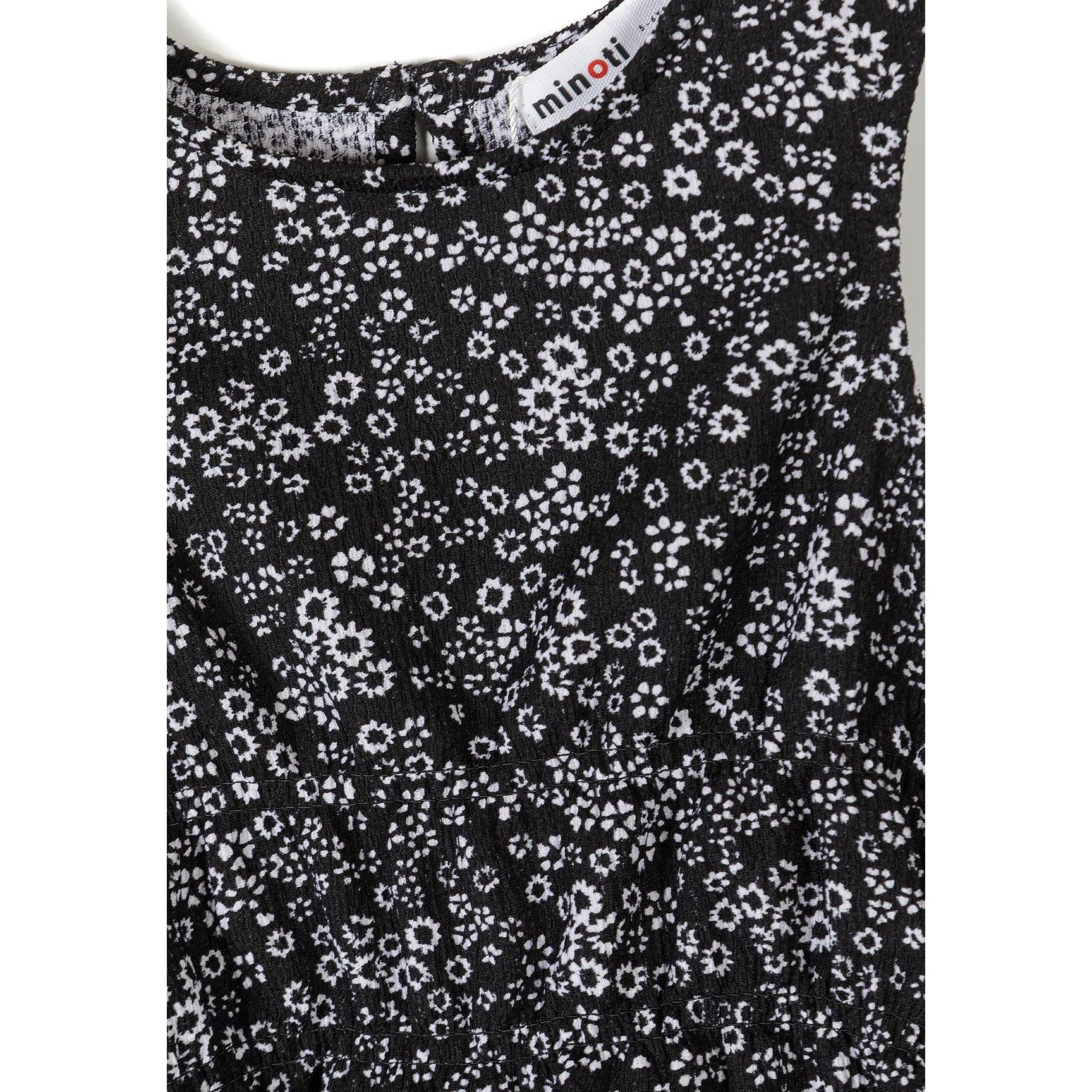 Detail shot of black sleeveless top showing Minoti label and small white floral print pattern on jersey fabric