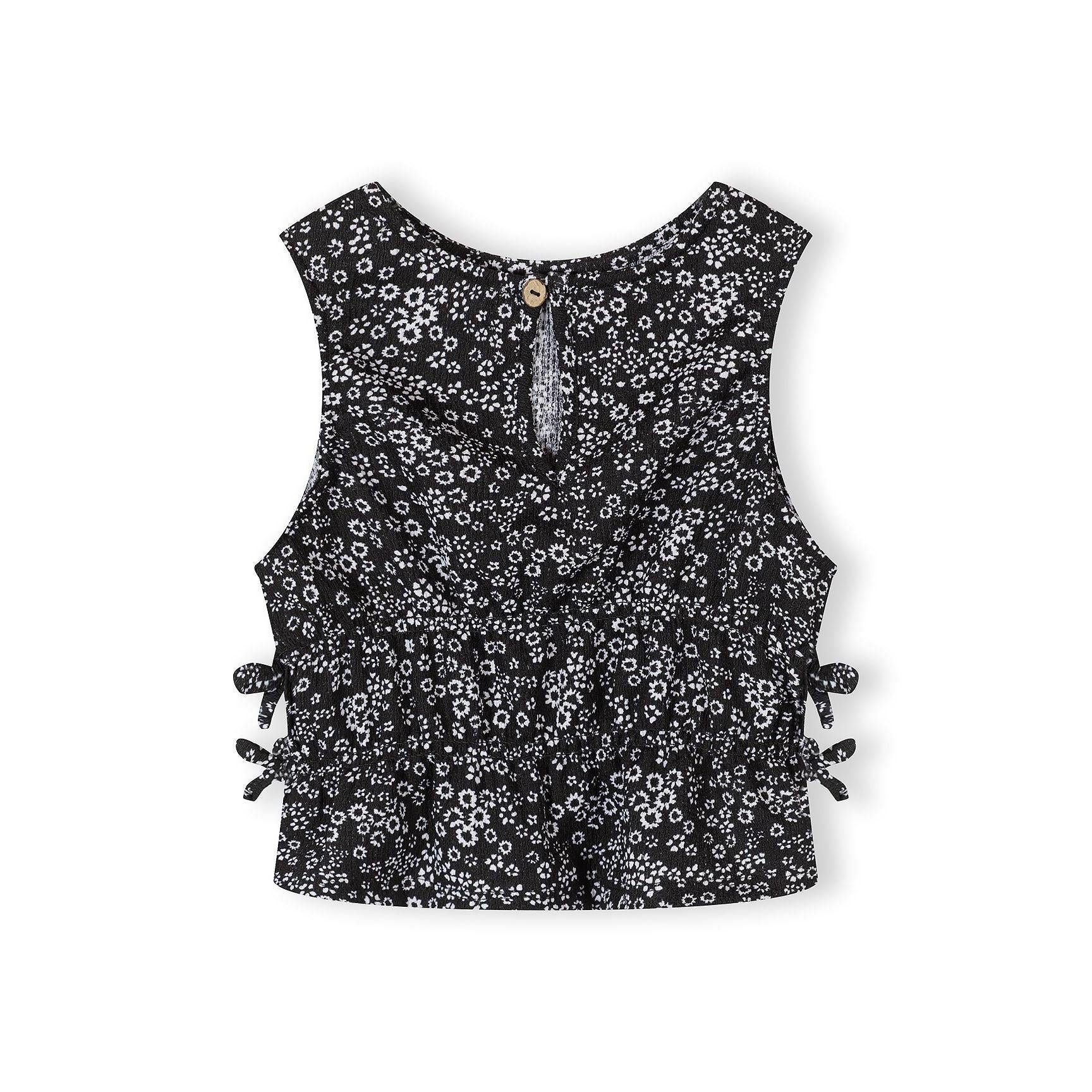 Detail shot of black sleeveless top showing Minoti label and small white floral print pattern on jersey fabric