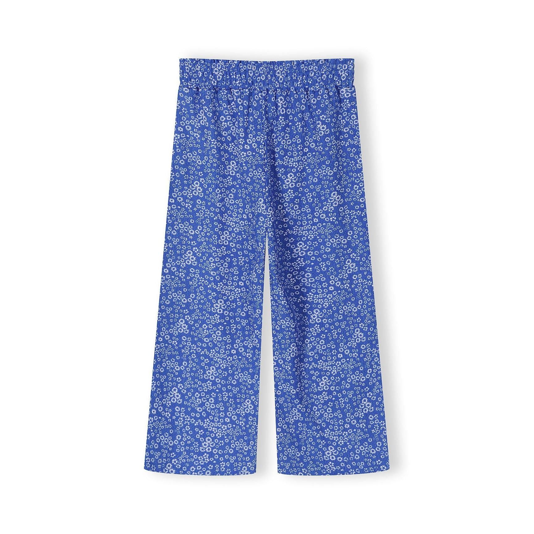 Close-up detail of blue floral jersey fabric showing Minoti brand label and small white flower pattern texture