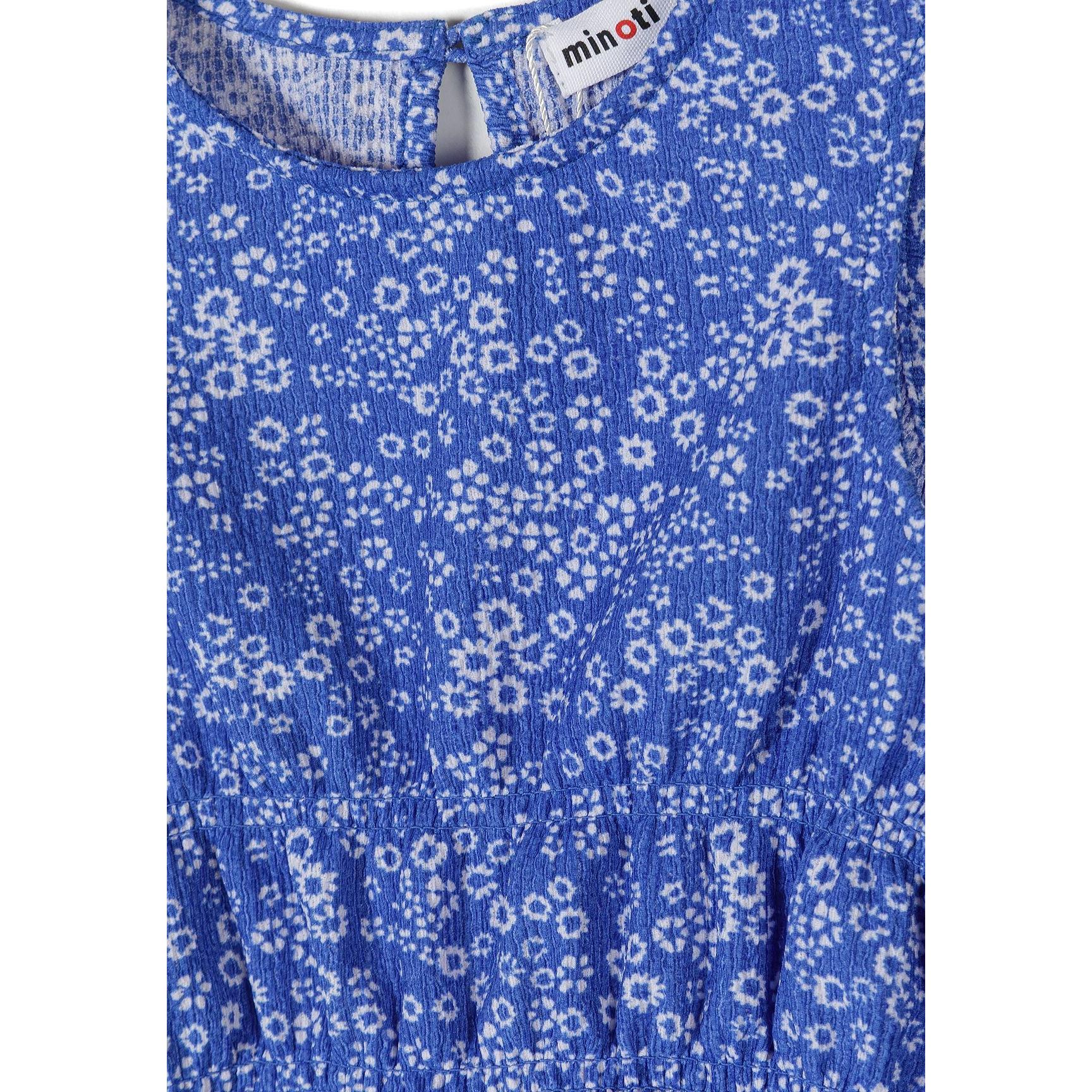 Close-up detail of blue floral jersey fabric showing Minoti brand label and small white flower pattern texture