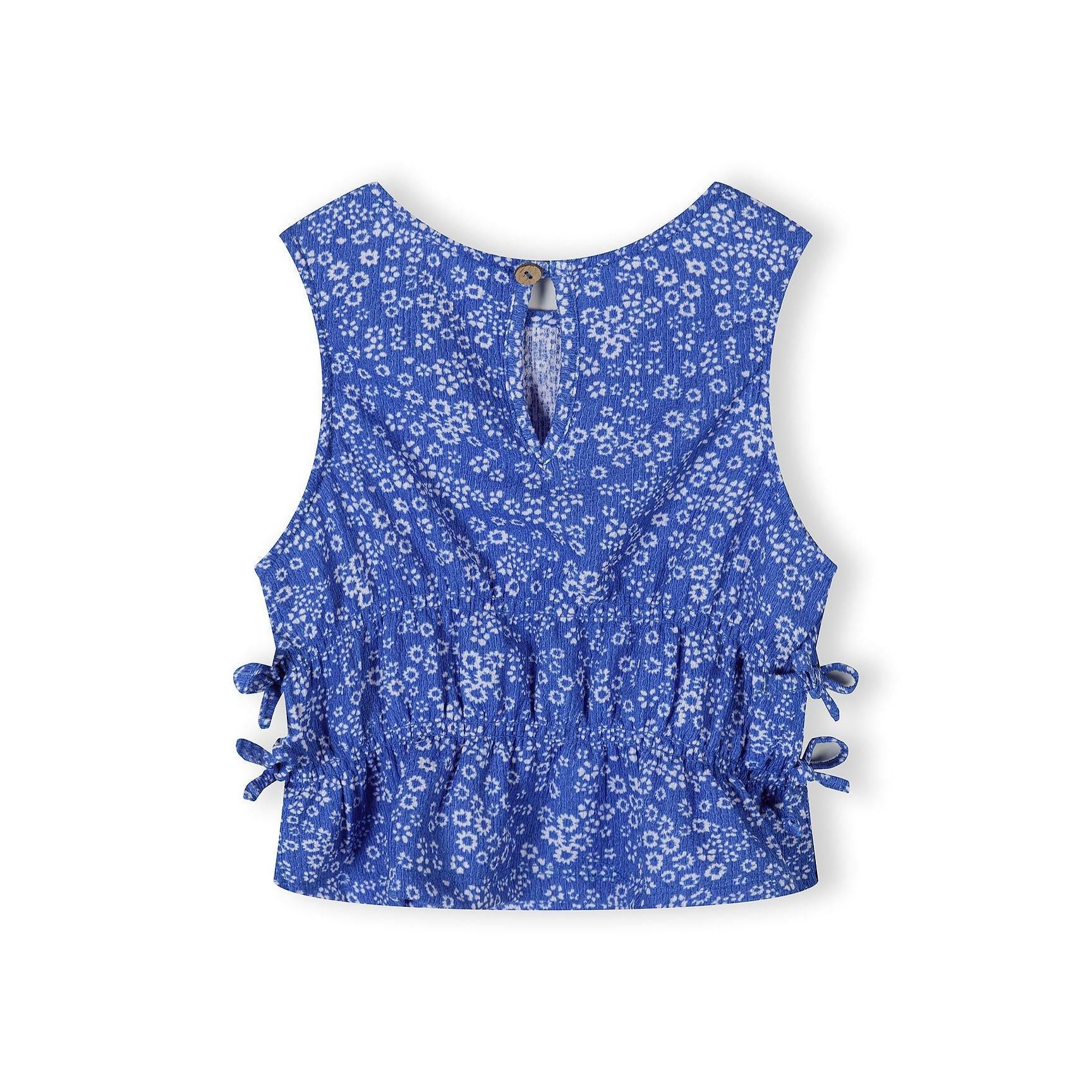 Close-up detail of blue floral jersey fabric showing Minoti brand label and small white flower pattern texture