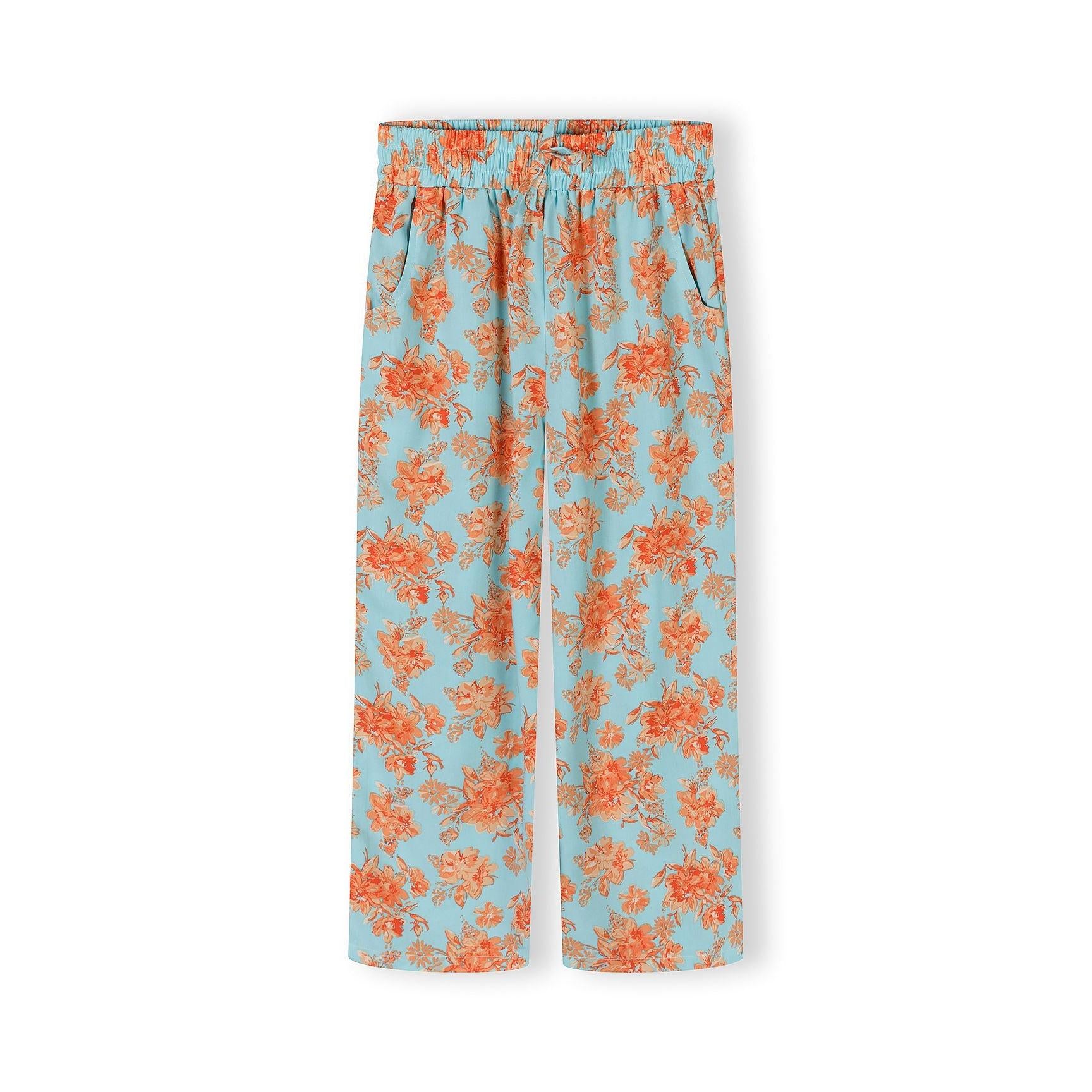 Close-up detail of light blue viscose trousers with orange floral print showing elasticated waistband and wide-leg cut