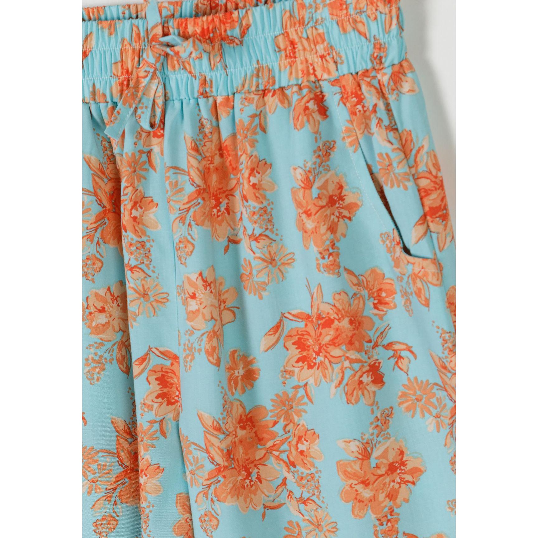 Close-up detail of light blue viscose trousers with orange floral print showing elasticated waistband and wide-leg cut