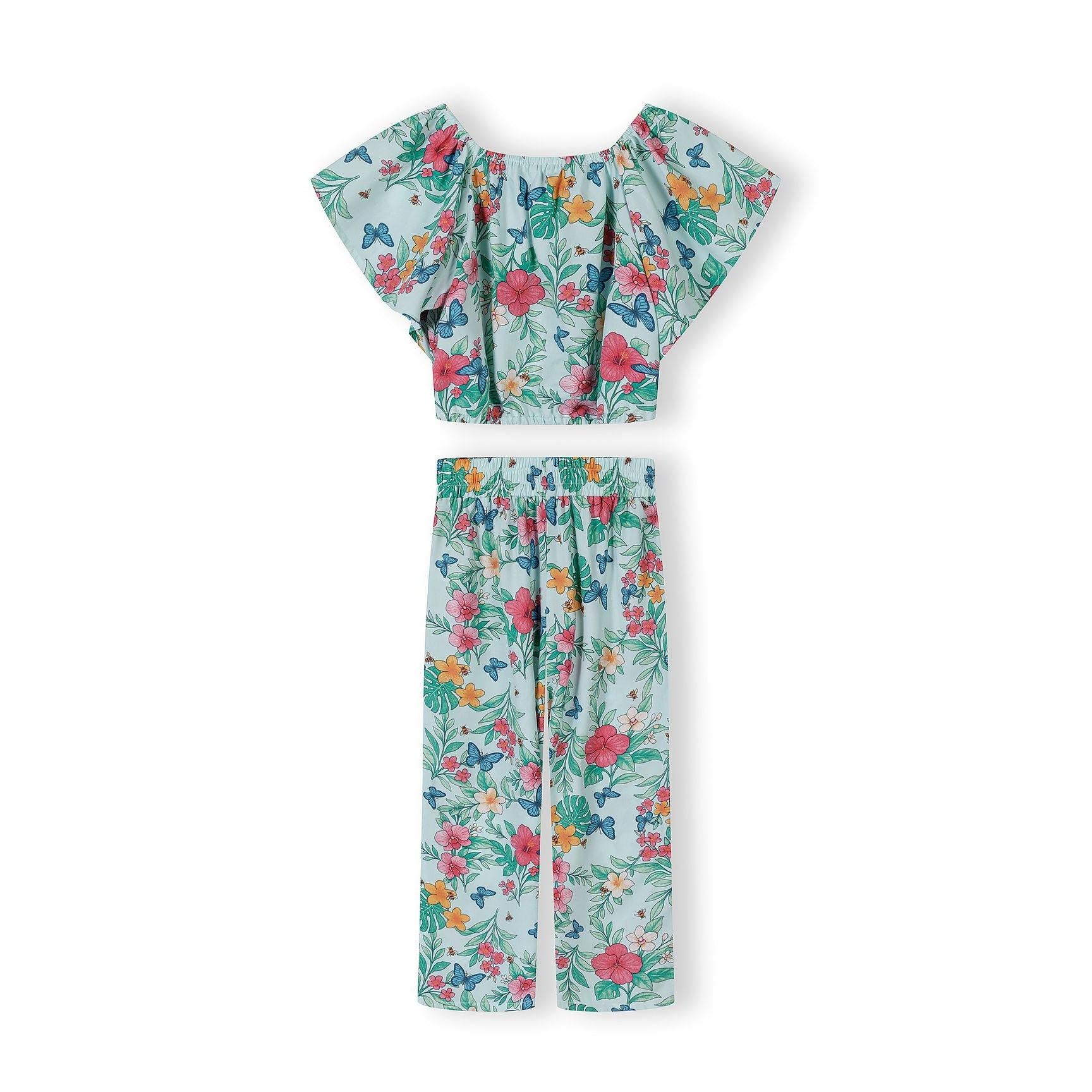 Close-up detail of mint tropical print pattern on wide-leg trousers showing colorful hibiscus flowers, butterflies and tropical leaves