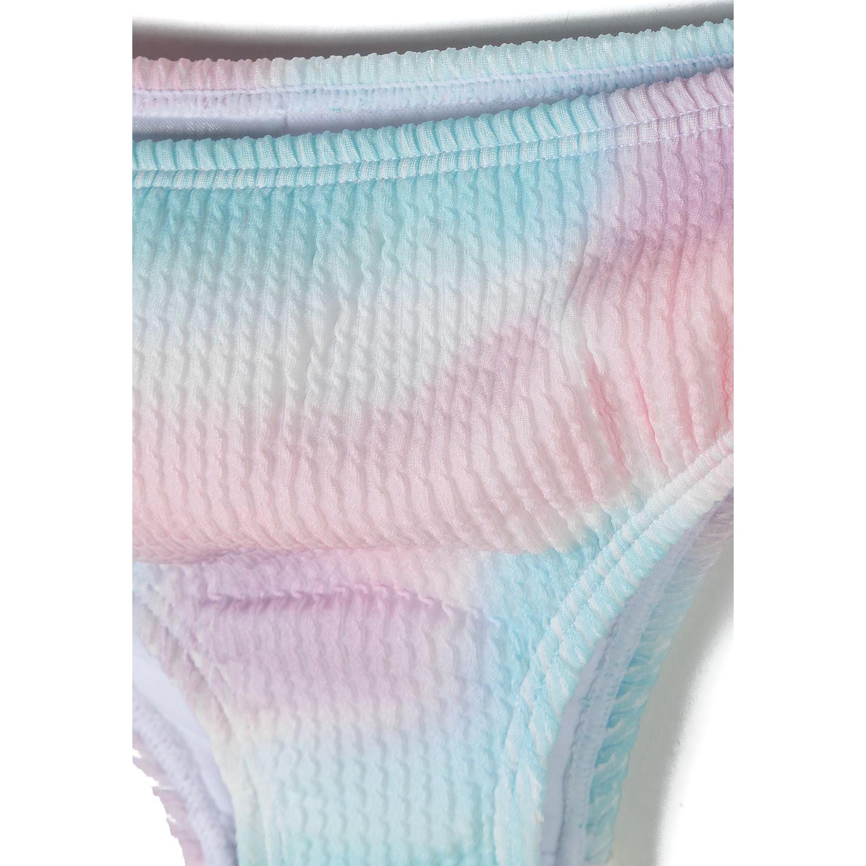 Detail view of bikini top showing adjustable pink buckle closure and ribbed fabric texture in tie-dye pattern against white background