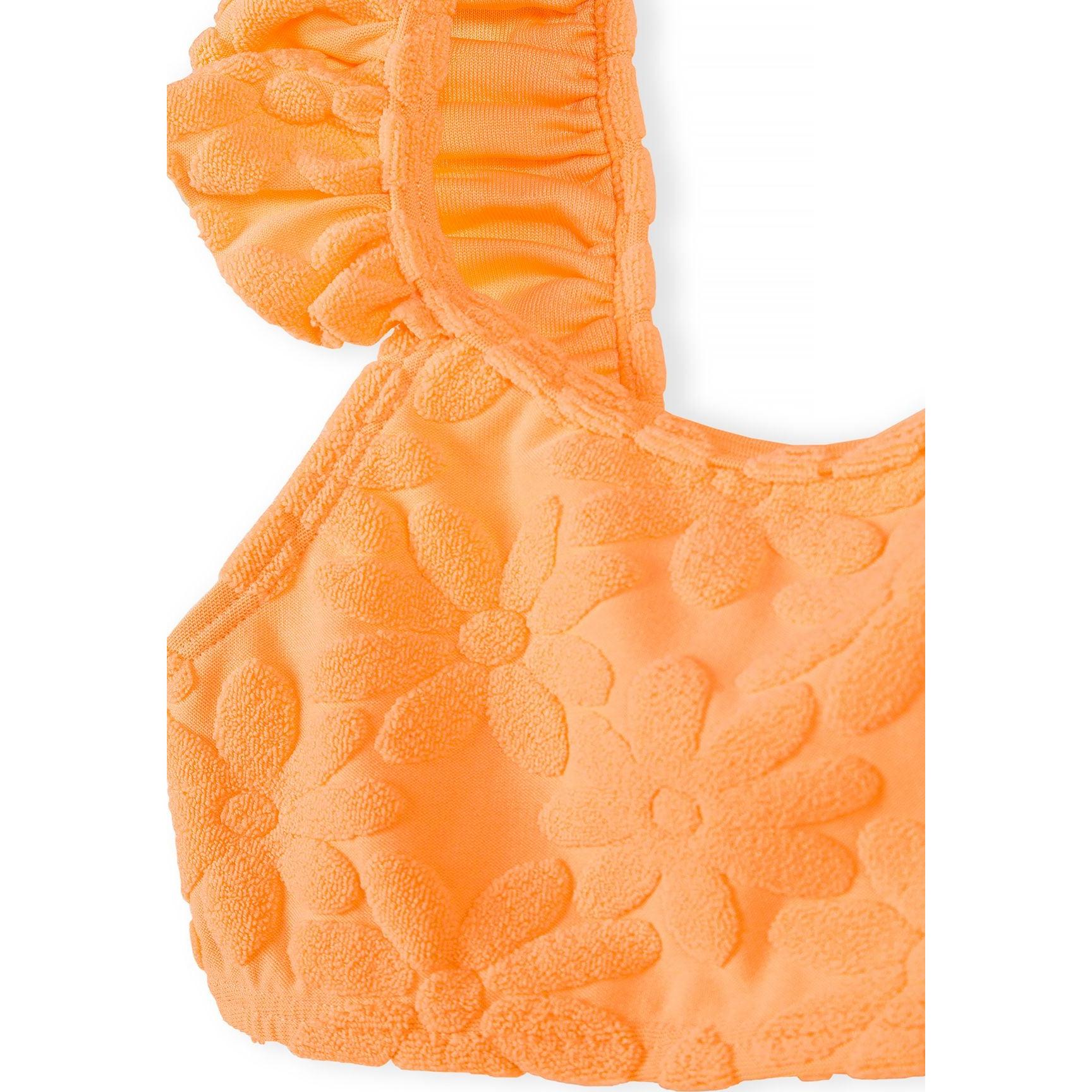 Detail shot showing textured floral jacquard pattern and frill trim construction on neon orange bikini fabric