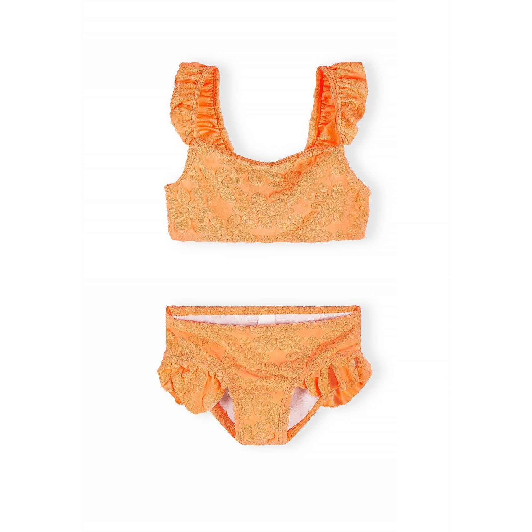 Detail shot of bright orange textured bikini top showing decorative raised dot pattern fabric and ruffle trim on shoulder strap against white background