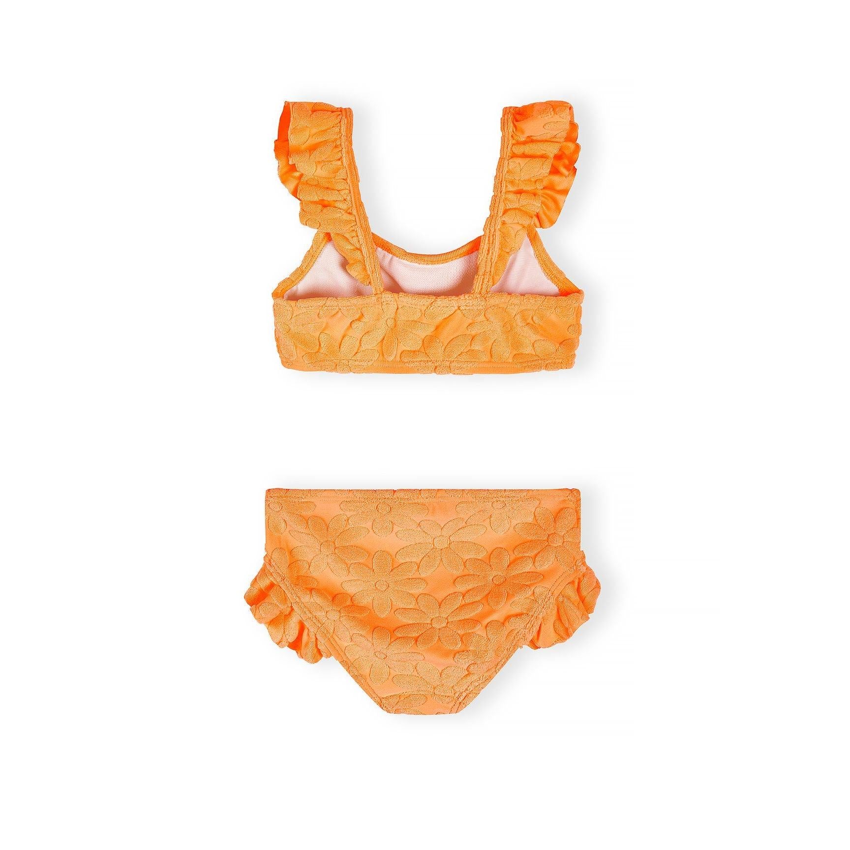 Detail shot of bright orange textured bikini top showing decorative raised dot pattern fabric and ruffle trim on shoulder strap against white background